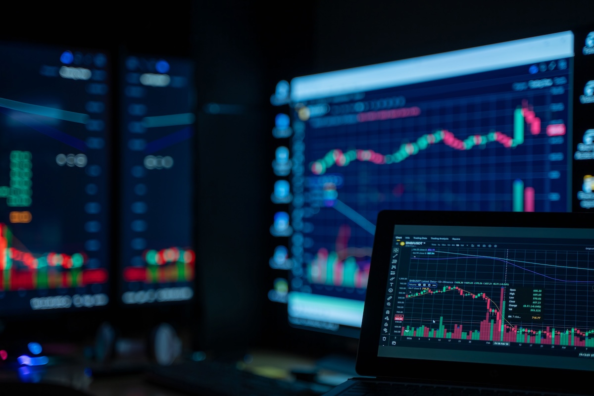 Monitors displaying stock market charts in a dimly lit room, perfect for finance and trading themes.