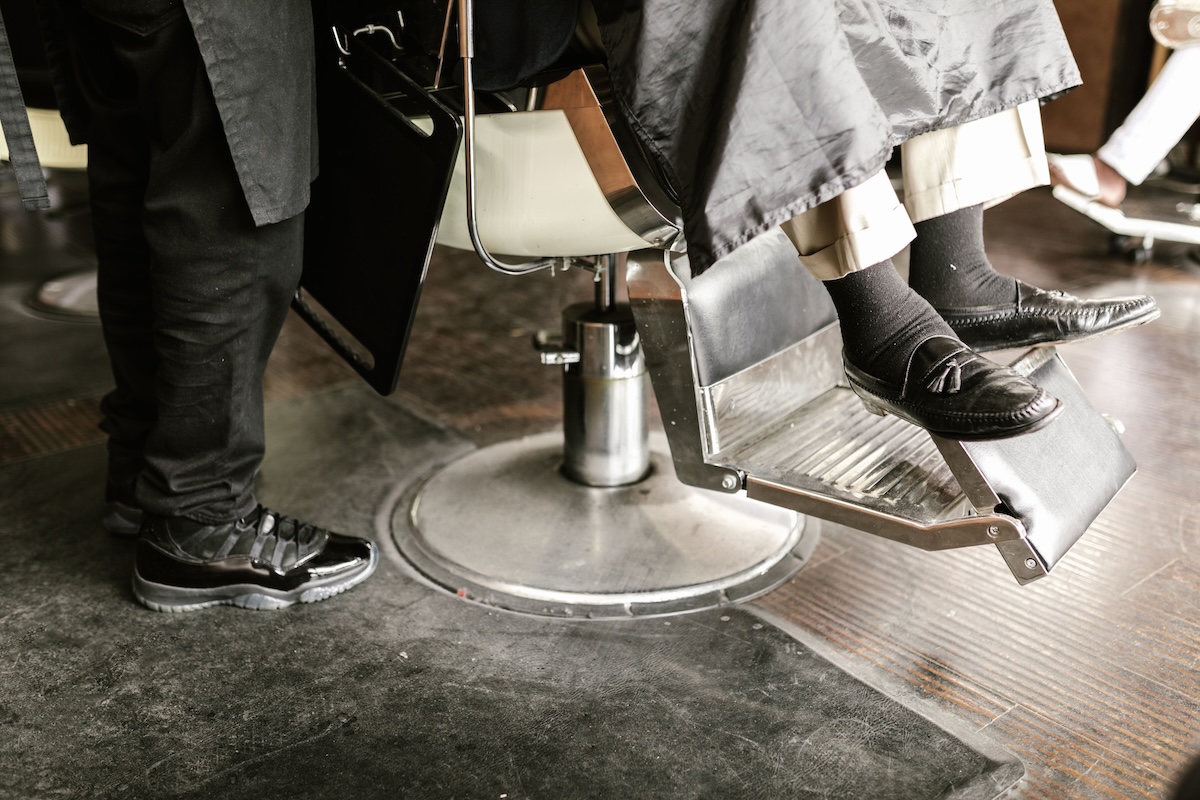 Close-up of leather loafers resting in a barber chair, showcasing a classic barbershop interior with polished footwear and sleek aesthetics.