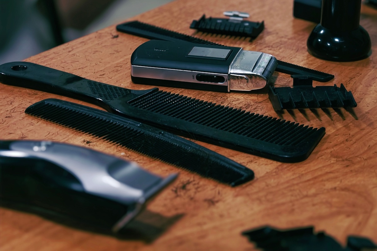 Close-up of barber tools like combs and clippers on a wooden table, creating a traditional grooming setup.