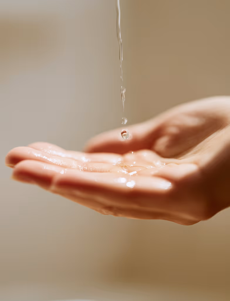Close-up of water droplets falling into an open hand against a blurred background.