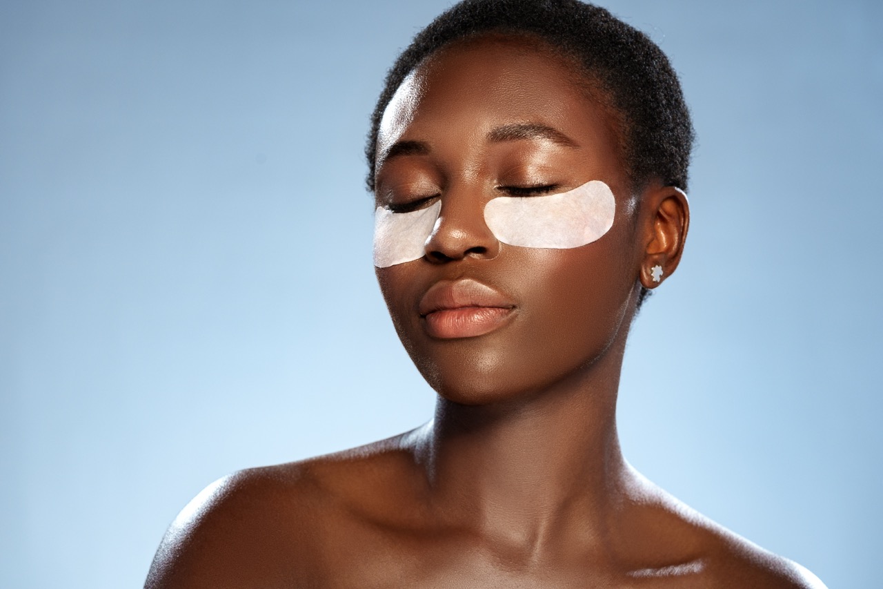 Woman wearing under-eye patches during a calm skincare treatment