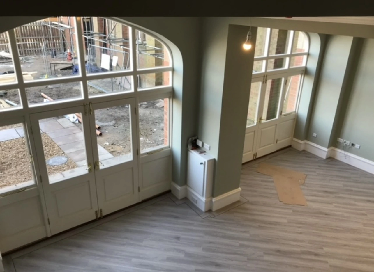 Interior of a room with tall painted sash windows and curved window heads.