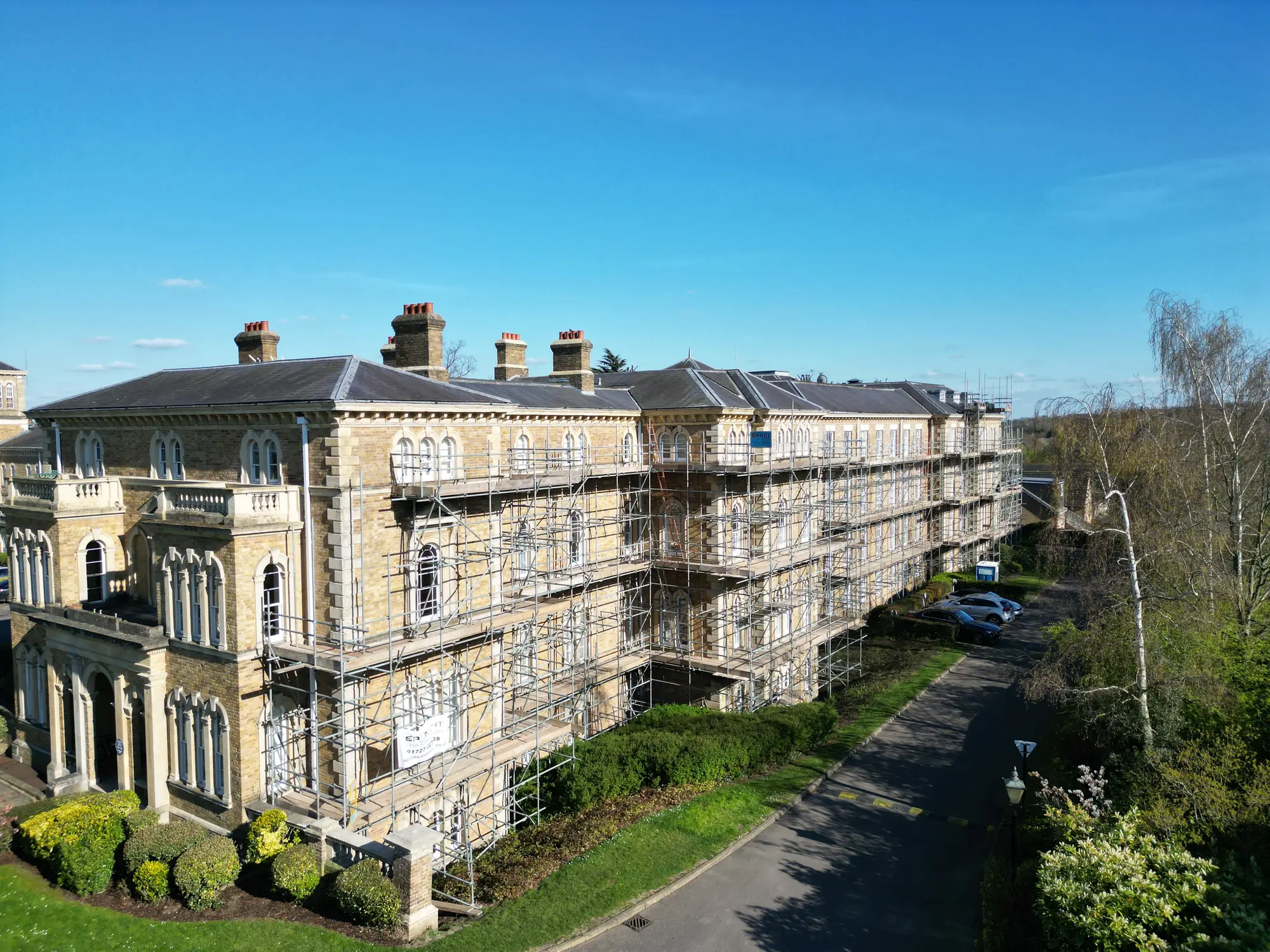 Scaffolding around a stone building with rows of sash windows.