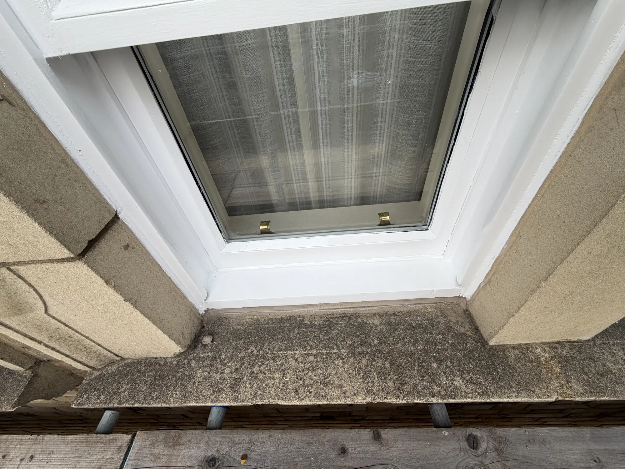 White painted sash window with two brass sash lifts above a stone sill.