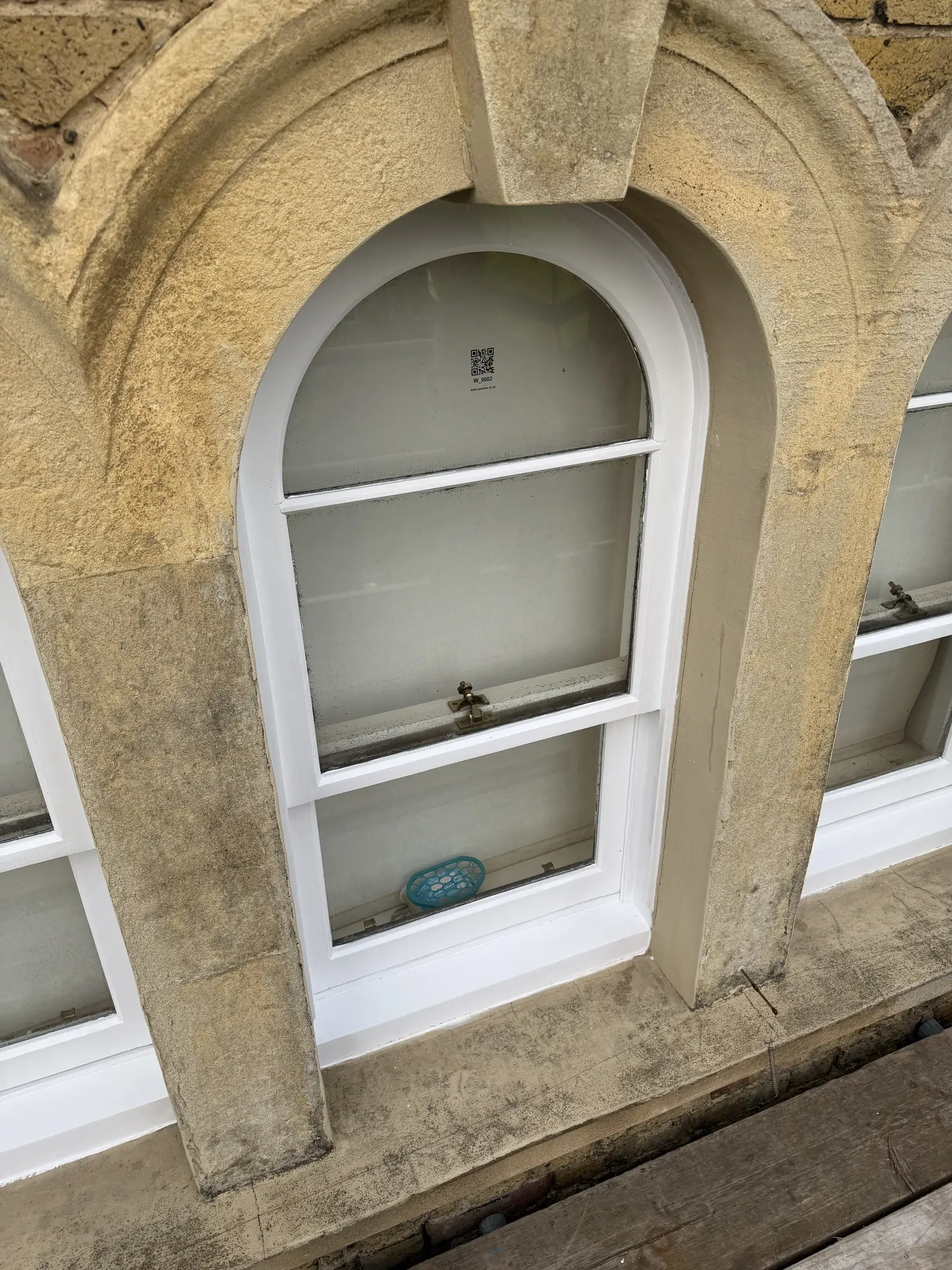 White painted arched sash window set in a stone surround.