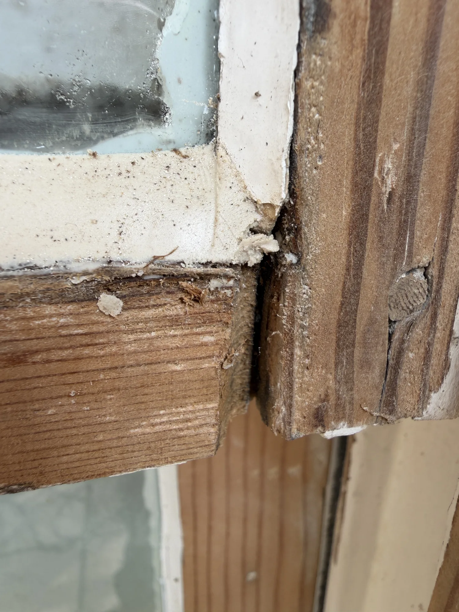 Exposed timber joint and glazing putty at the corner of a sash window.