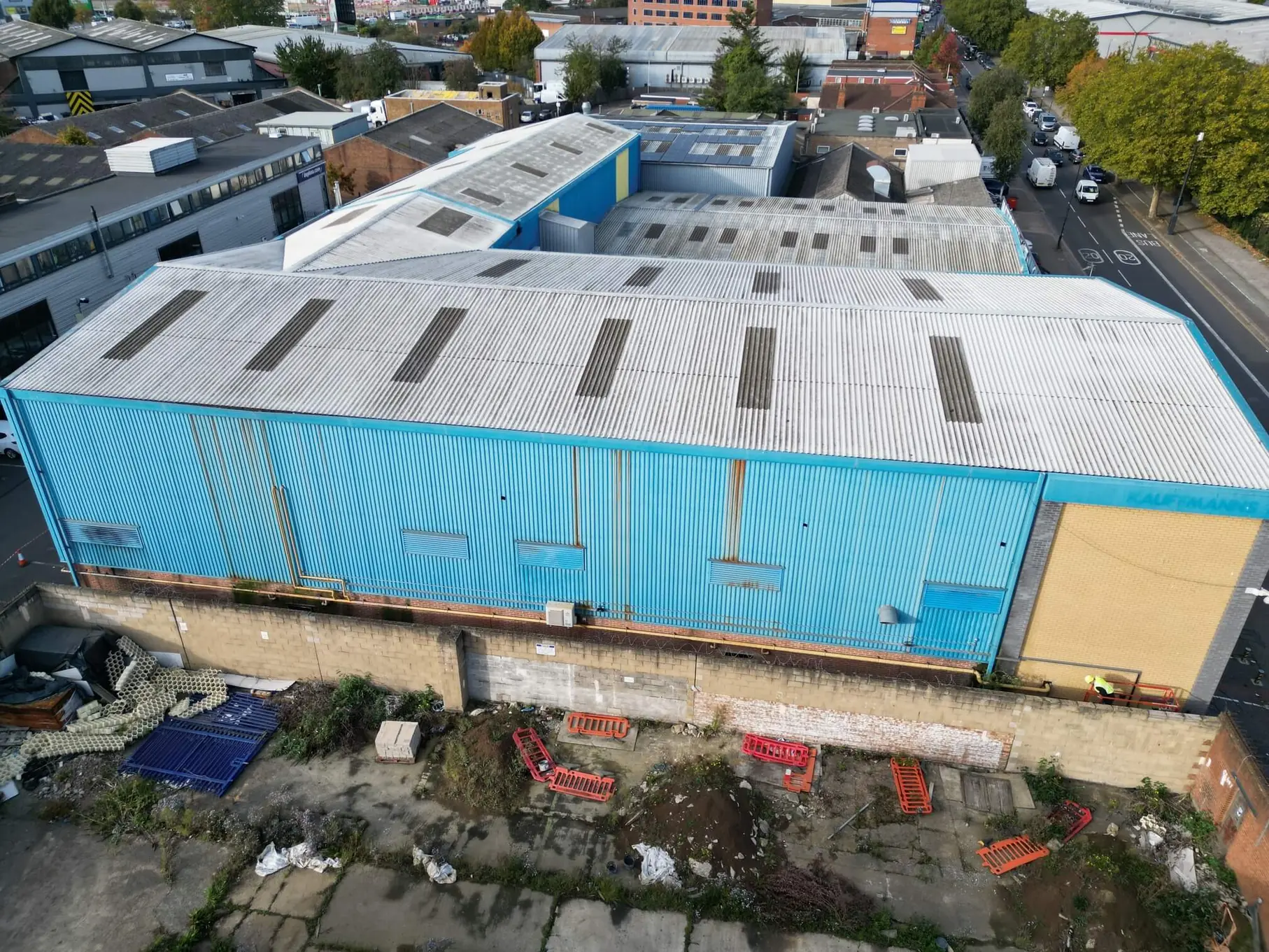 Aerial view of an industrial building with weathered blue metal cladding and a profiled roof.