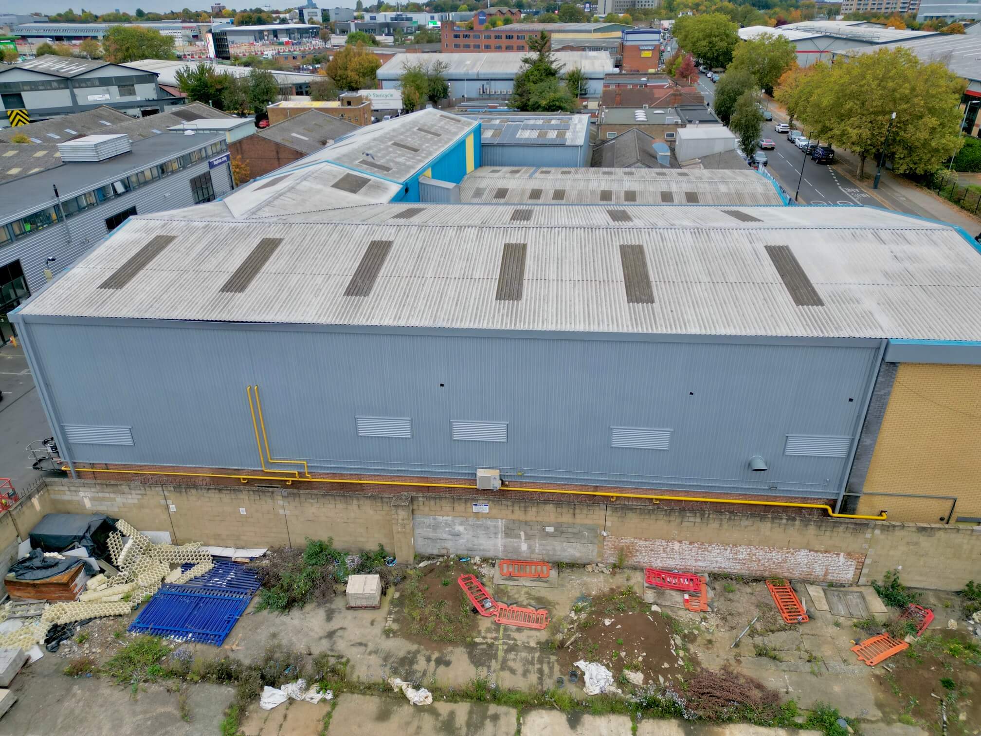 Aerial view of an industrial building with a uniform grey coating on its metal wall cladding.