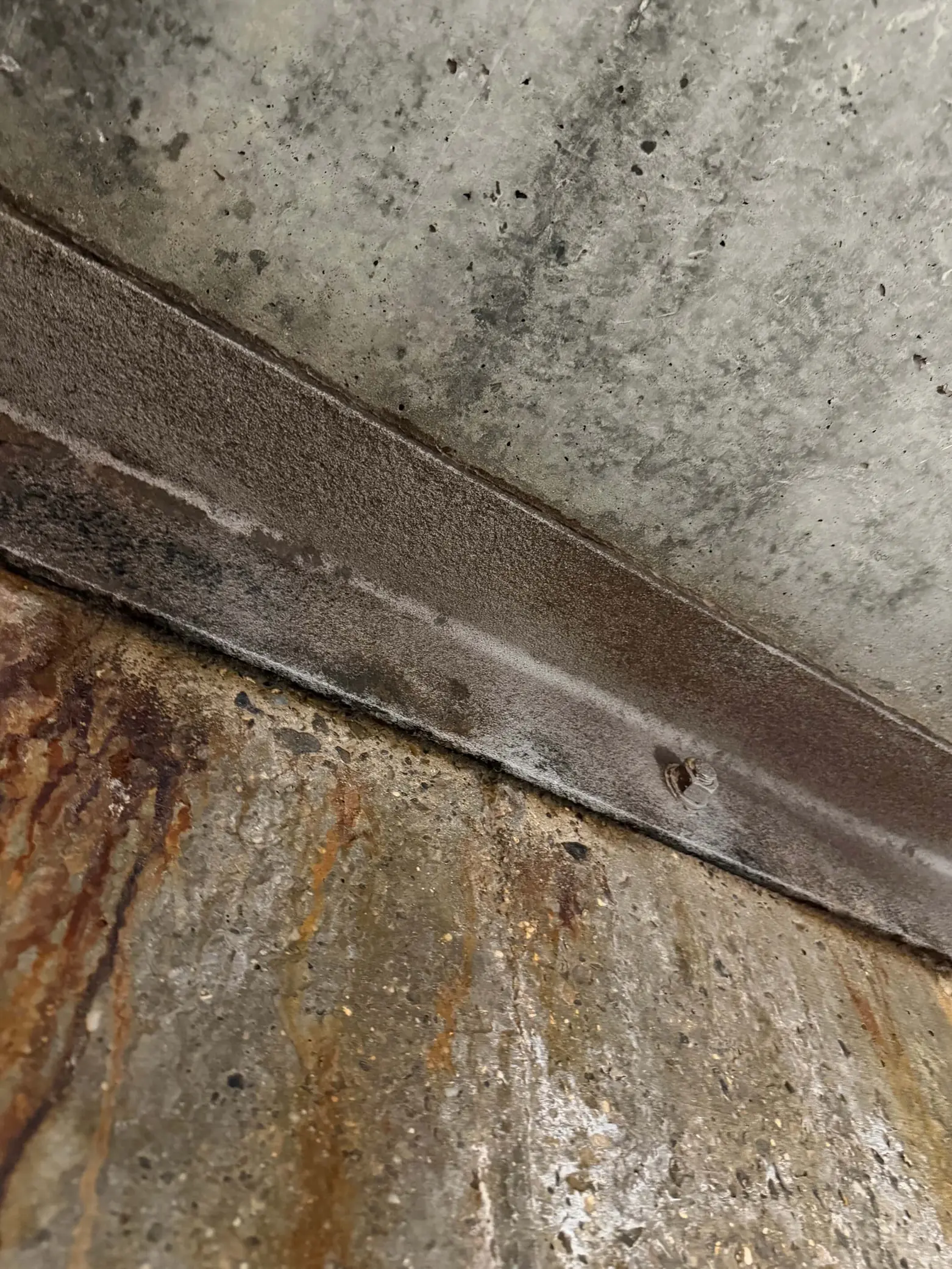 Exposed steel along a concrete ceiling edge after surface preparation.