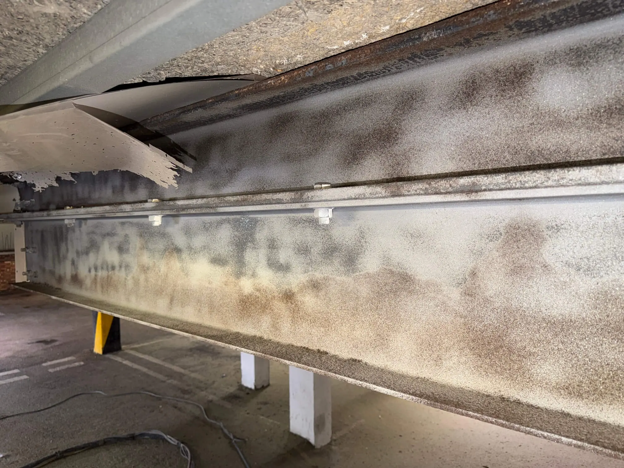 Prepared faces of structural steel beams inside a car park.