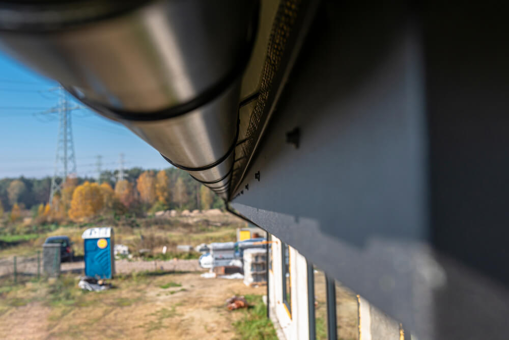 Close-up along dark guttering and fascia at the roof edge of a building.