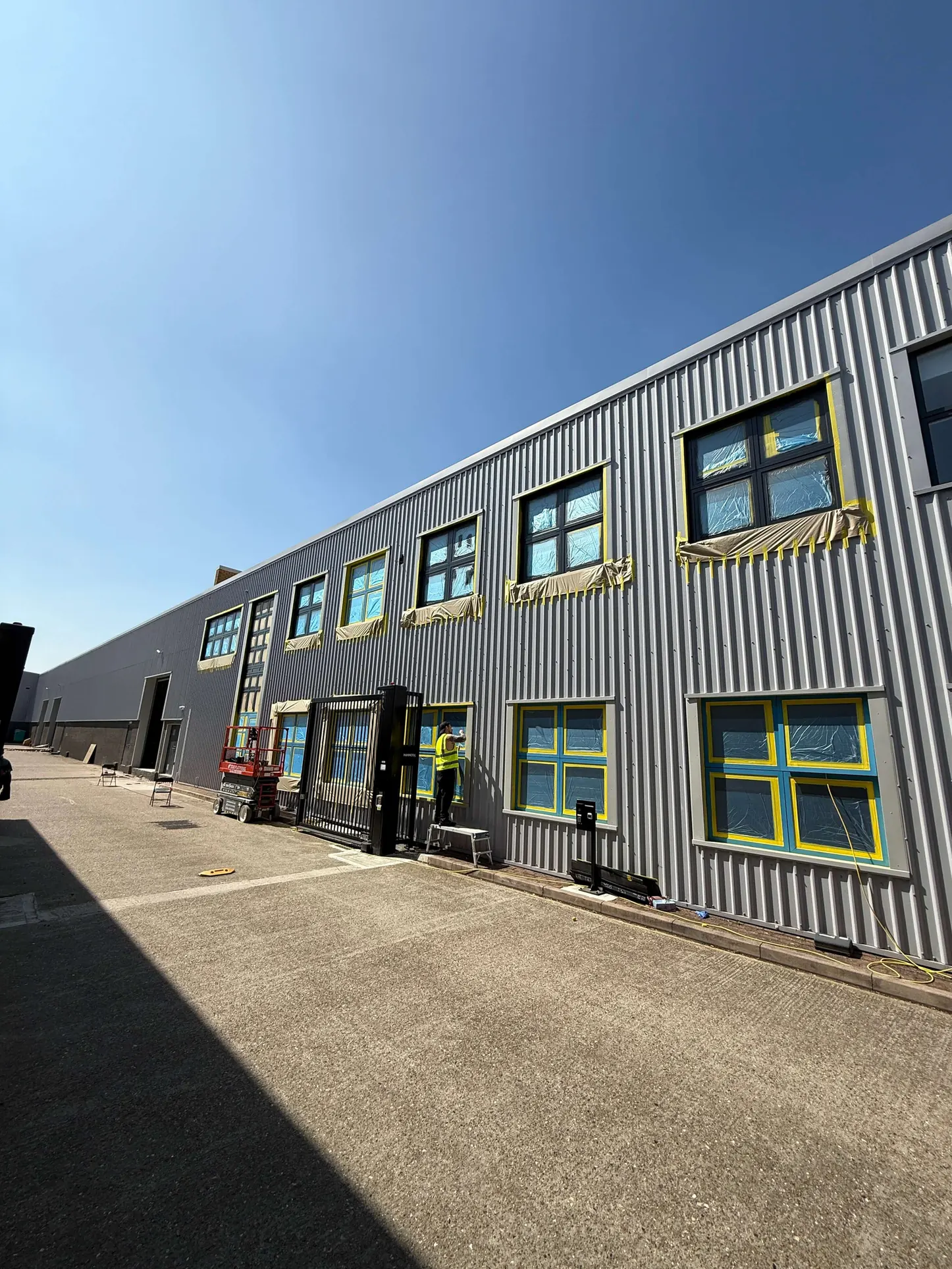 Two-storey industrial facade with masked windows during frame refurbishment