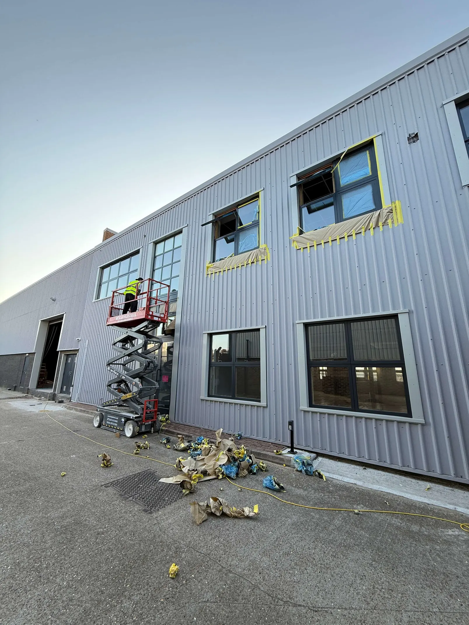 Raised scissor lift beside upper-floor windows during frame refurbishment