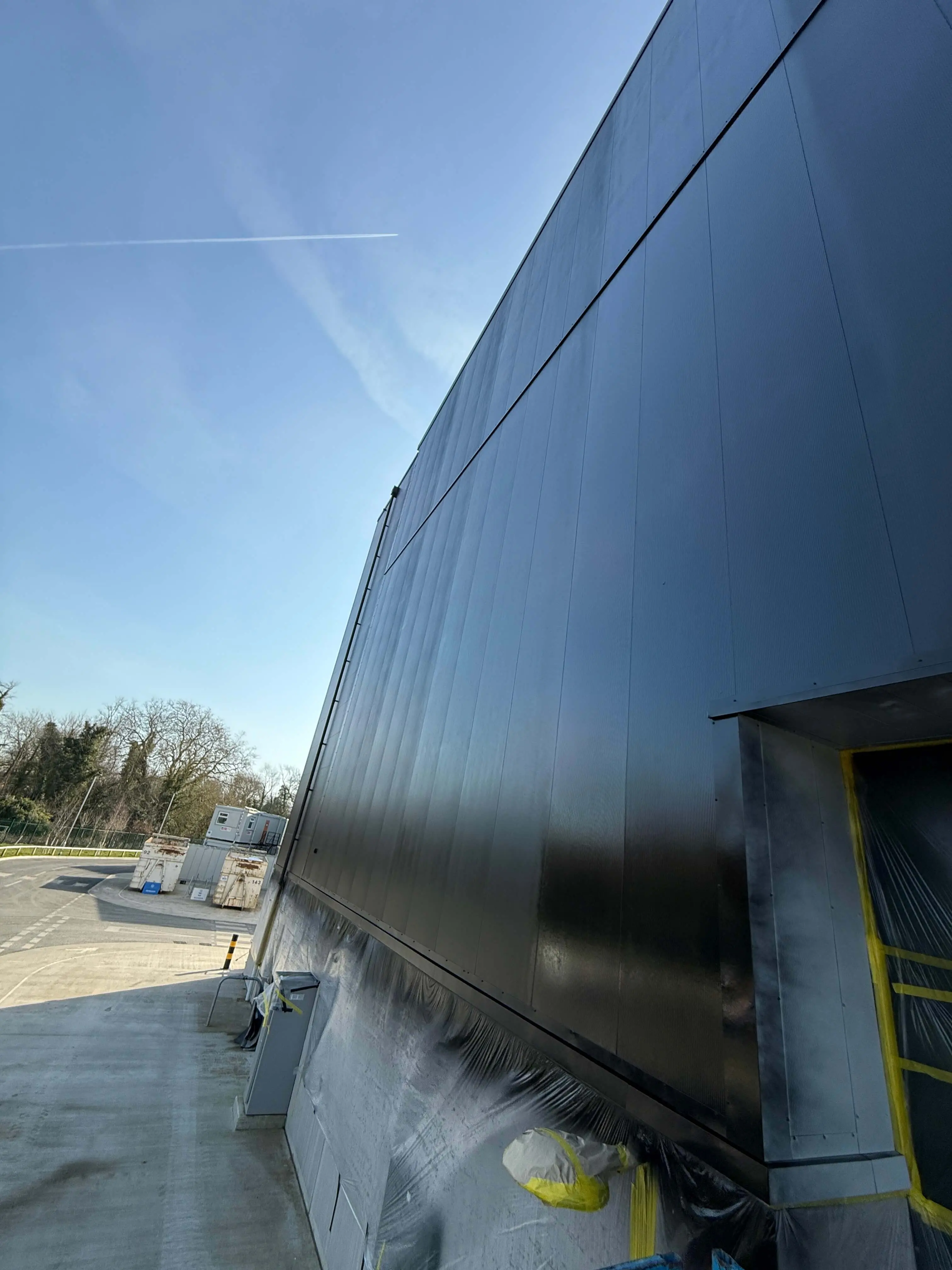 Dark industrial wall cladding above masked lower panels and windows.