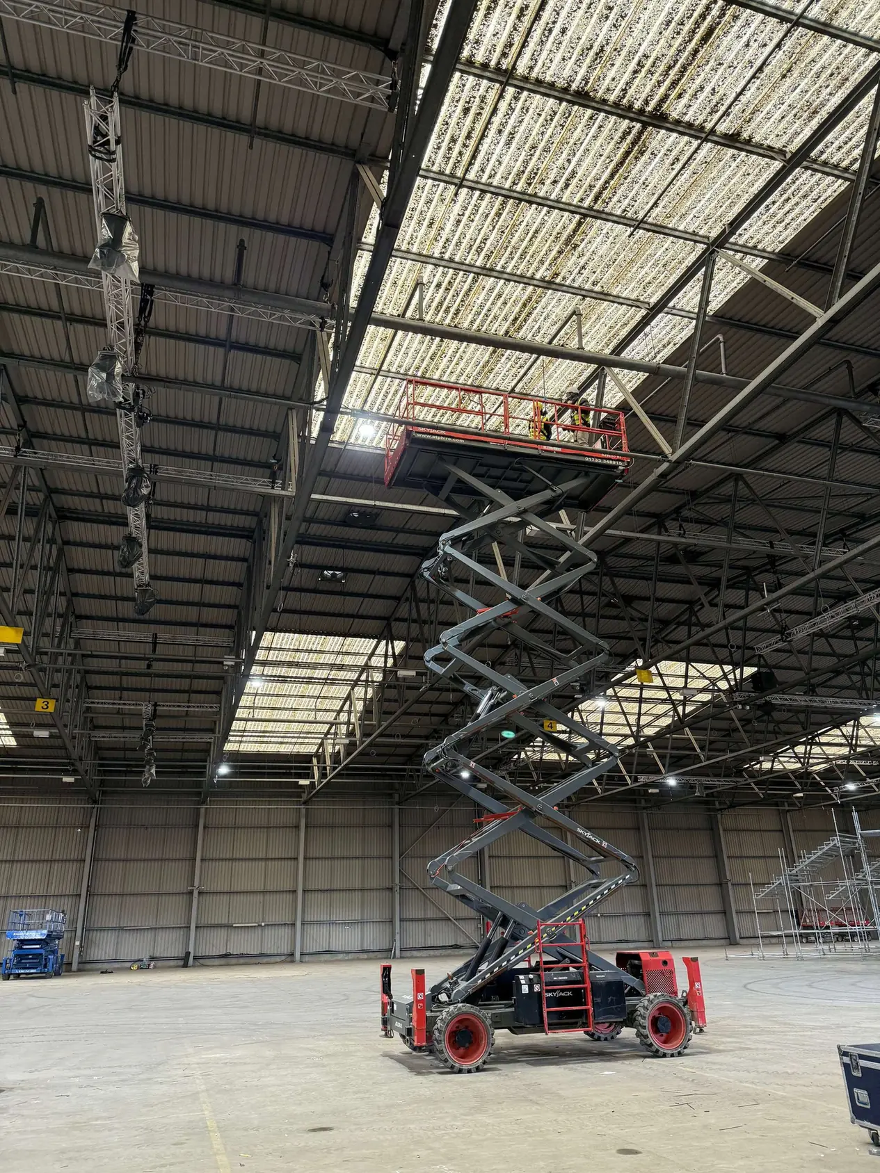 Extended scissor lift beneath rooflights and steel trusses at Deptford Store House