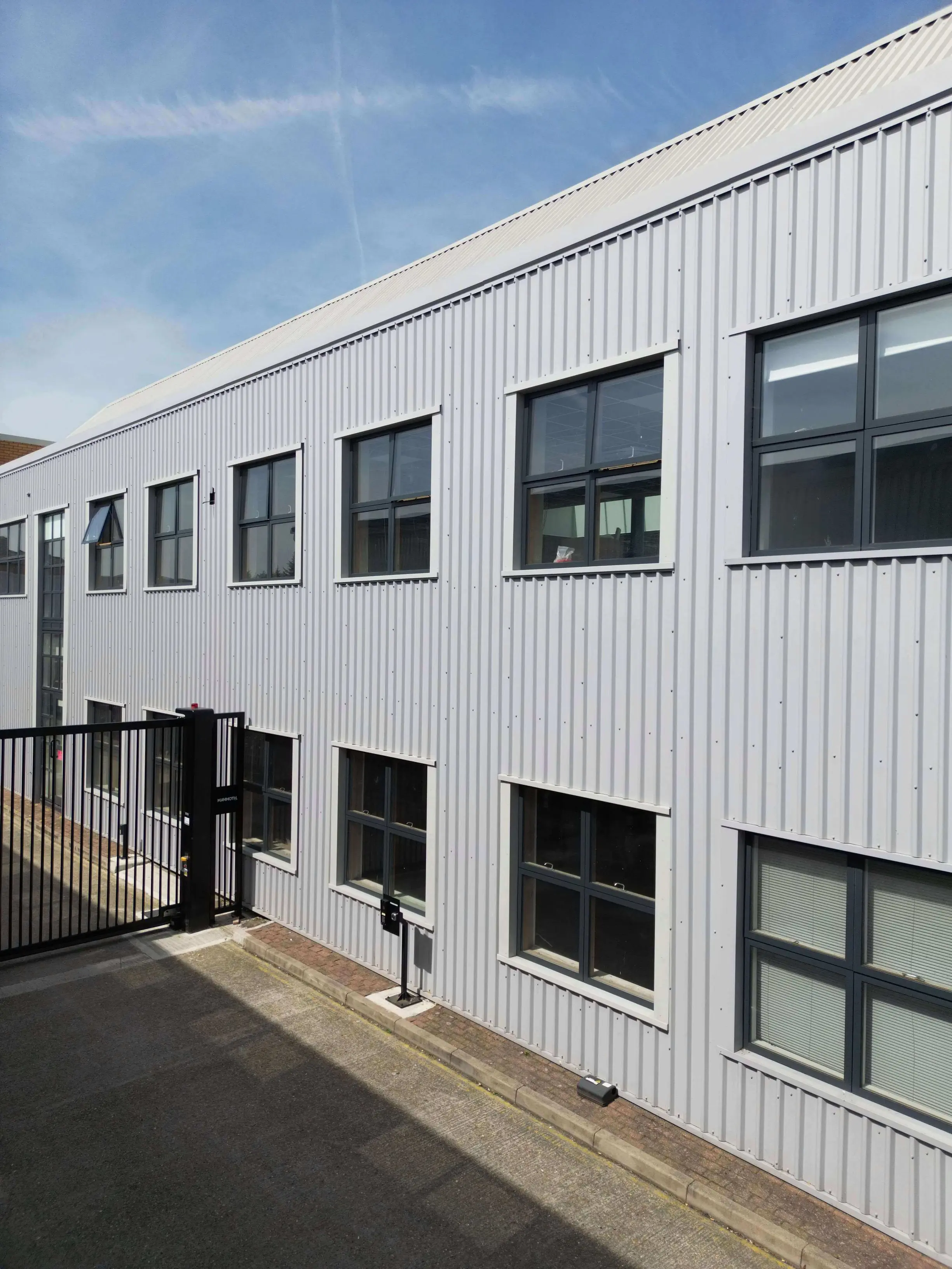 Dark window frames set into light grey profiled metal cladding.