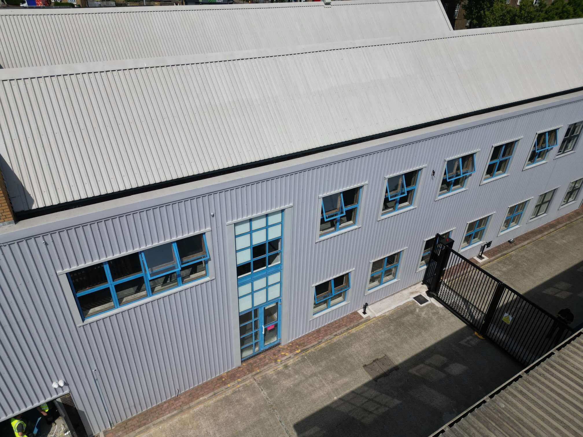 Aerial view of a commercial facade with blue window frames and a central glazed entrance.