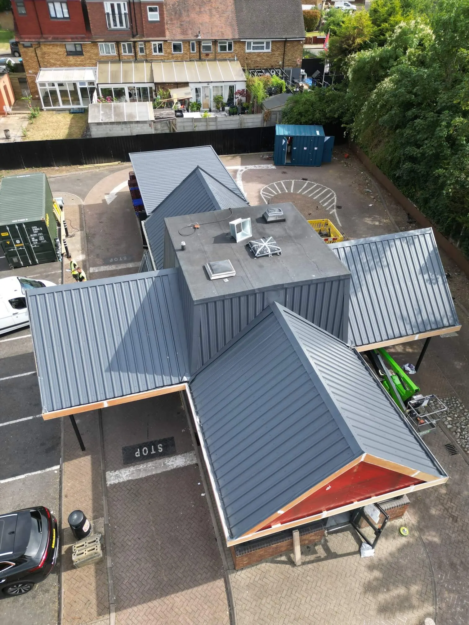 Overhead view of a grey-coated restaurant roof and adjoining car park.