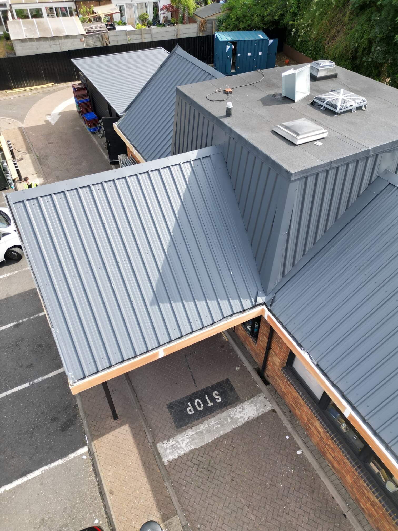 Grey roof slopes meeting a central plant enclosure on a commercial building.