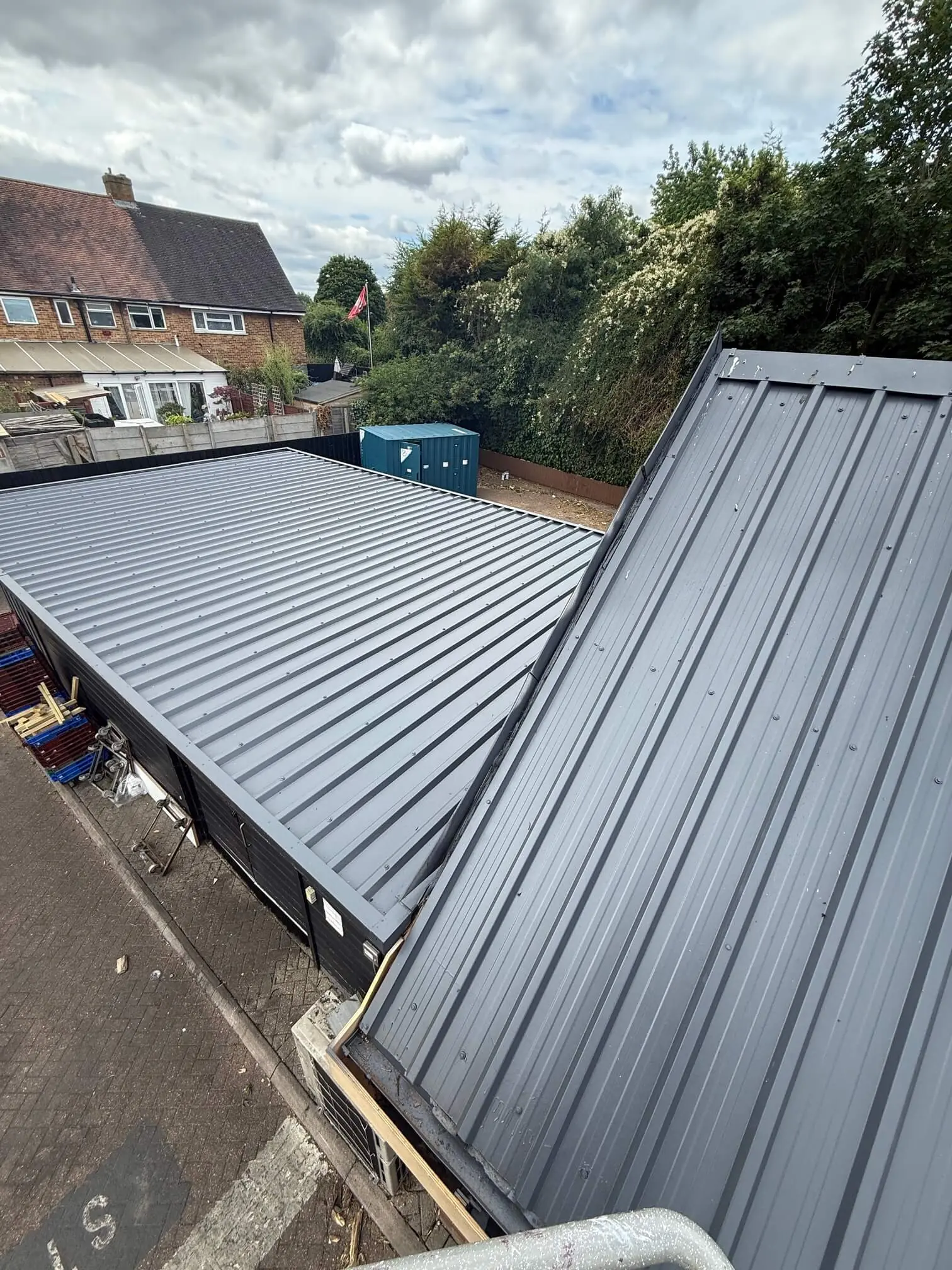 Grey roof slopes and flashings viewed from the junction between two roof sections.