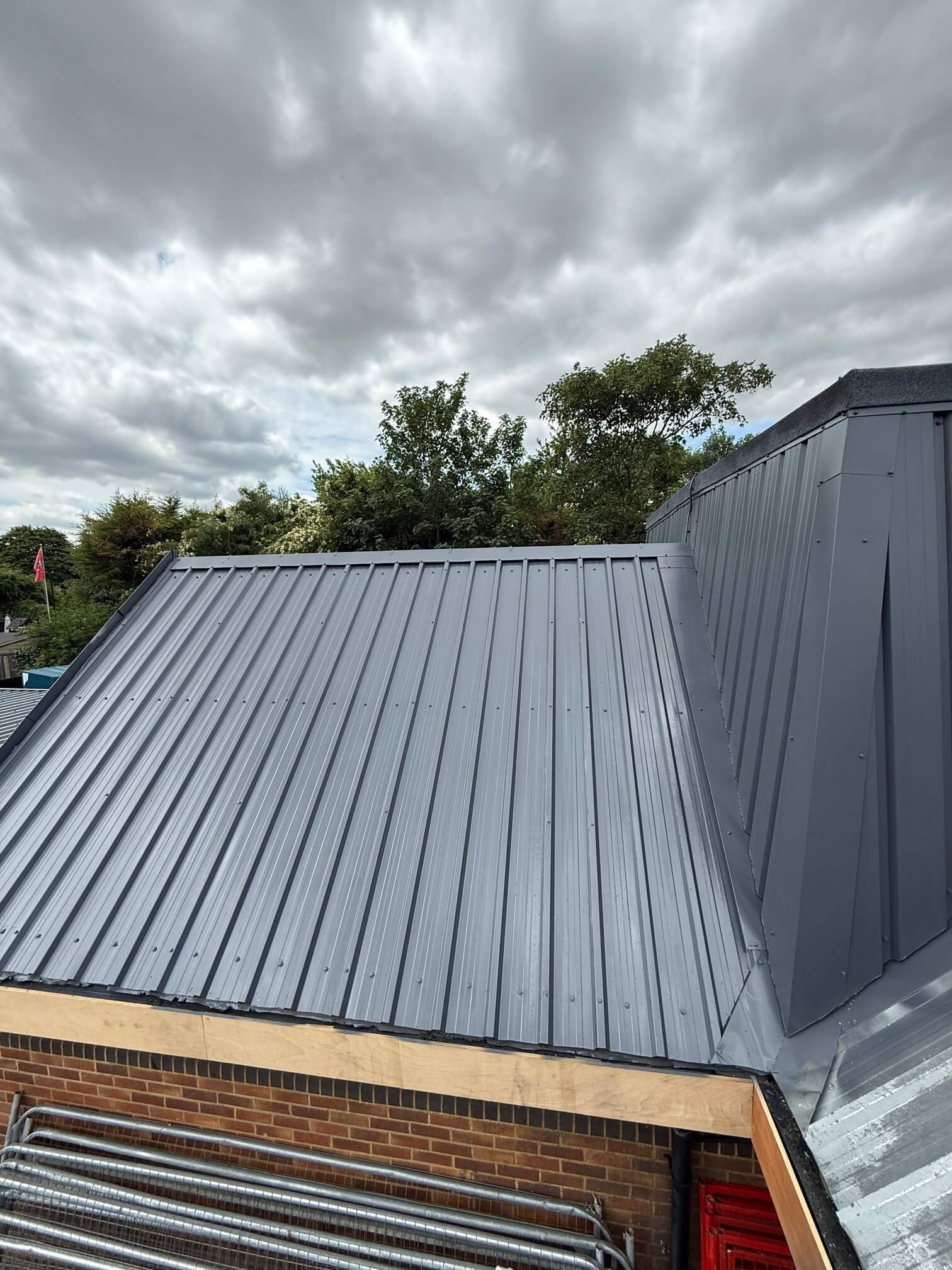 Grey profiled roof and central enclosure above a brick restaurant wall.