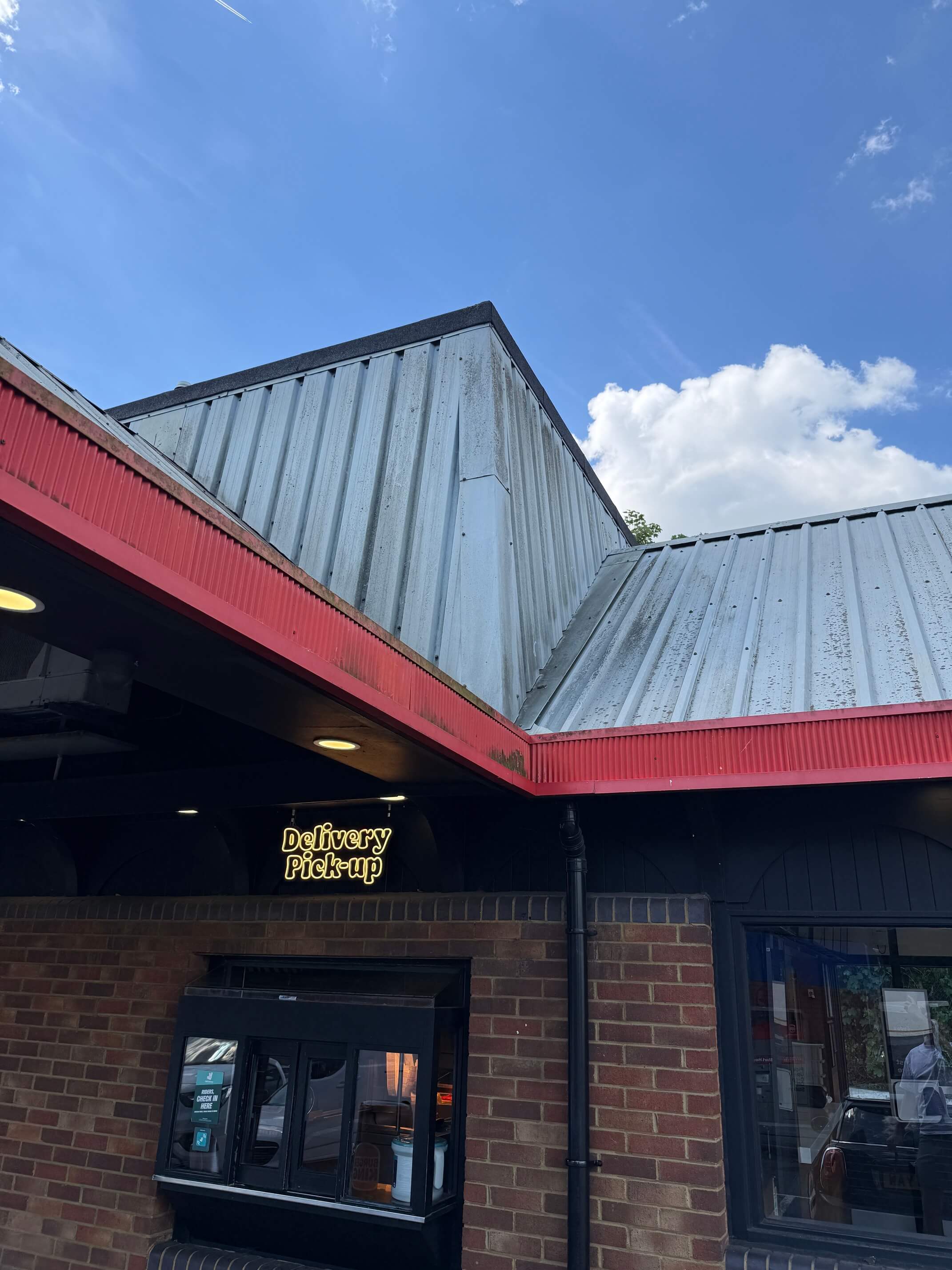 Weathered metal roof sheets above the red fascia of a Burger King drive-through.