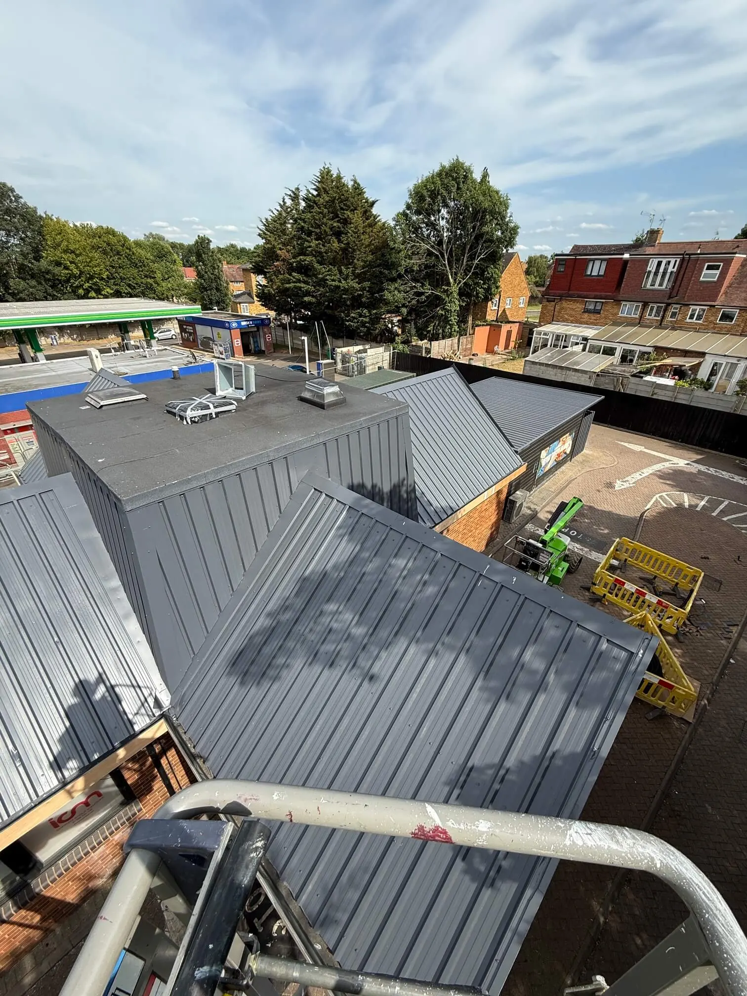 Grey metal roof slopes and central roof enclosure viewed from an access platform.
