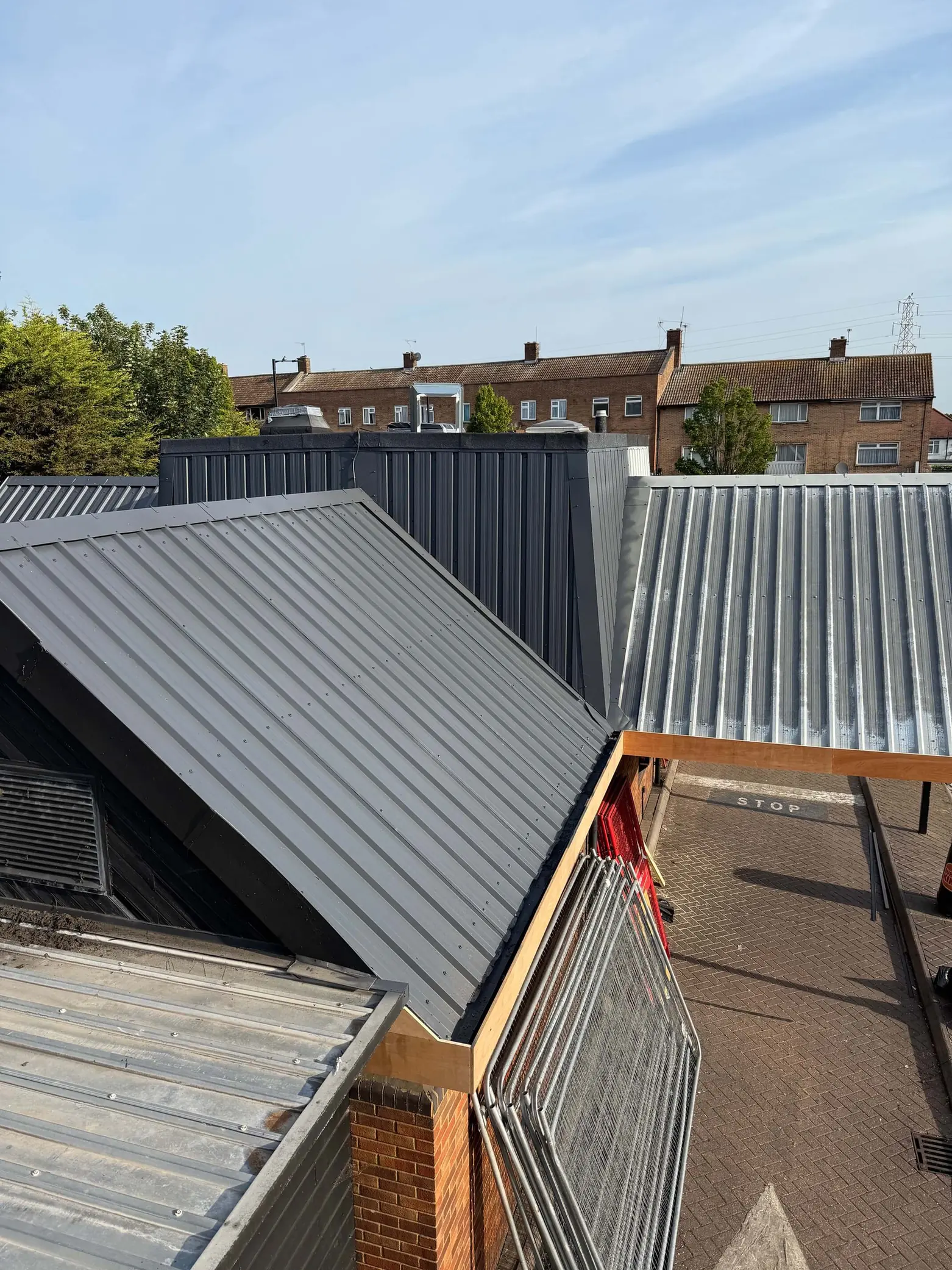 Grey-coated pitched roof beside a weathered adjoining roof section.