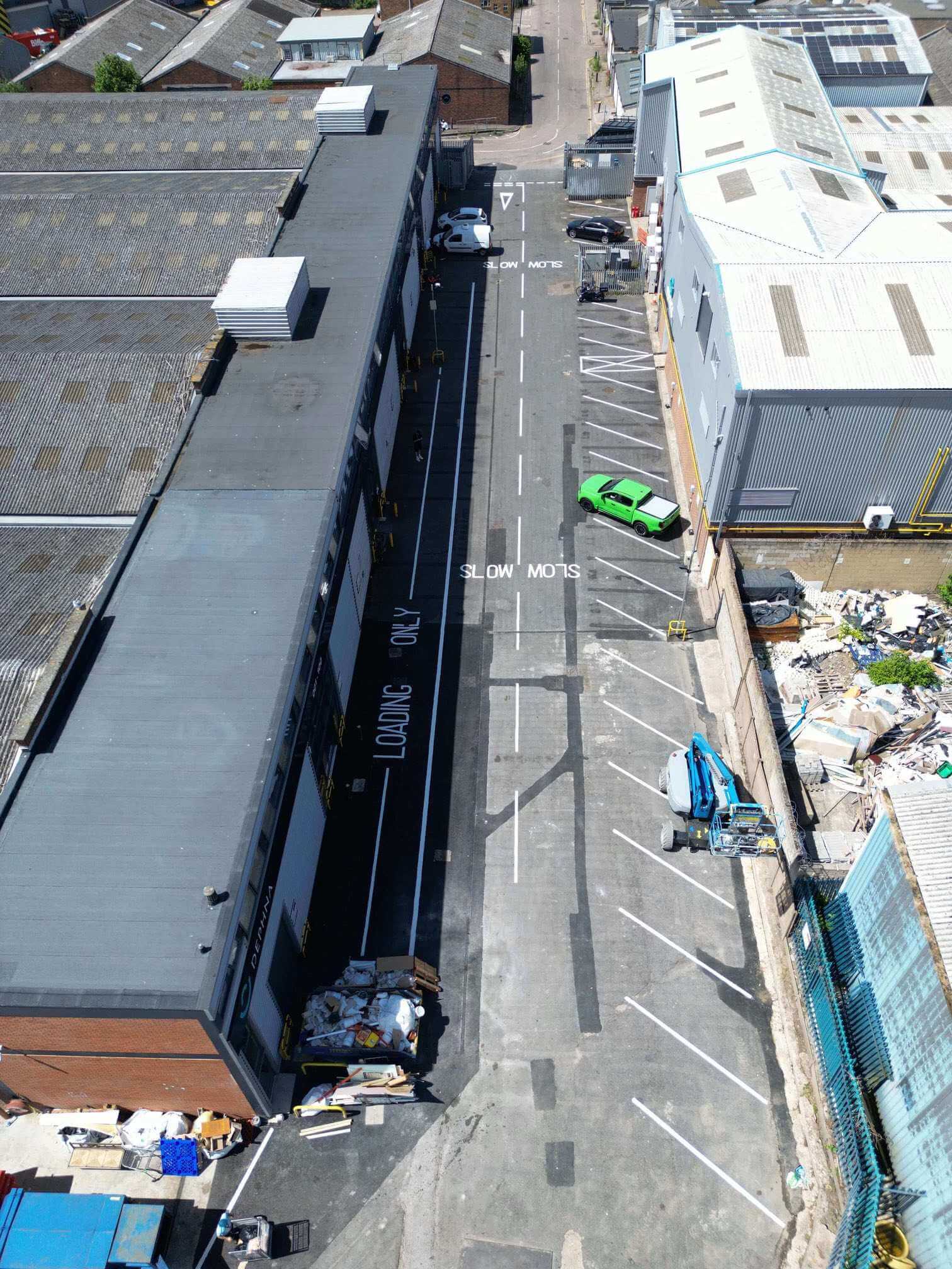 Aerial view along an industrial estate road with marked parking and loading bays.