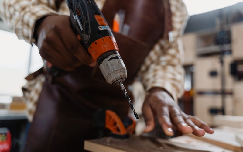 Craftsman using drill on wooden plank