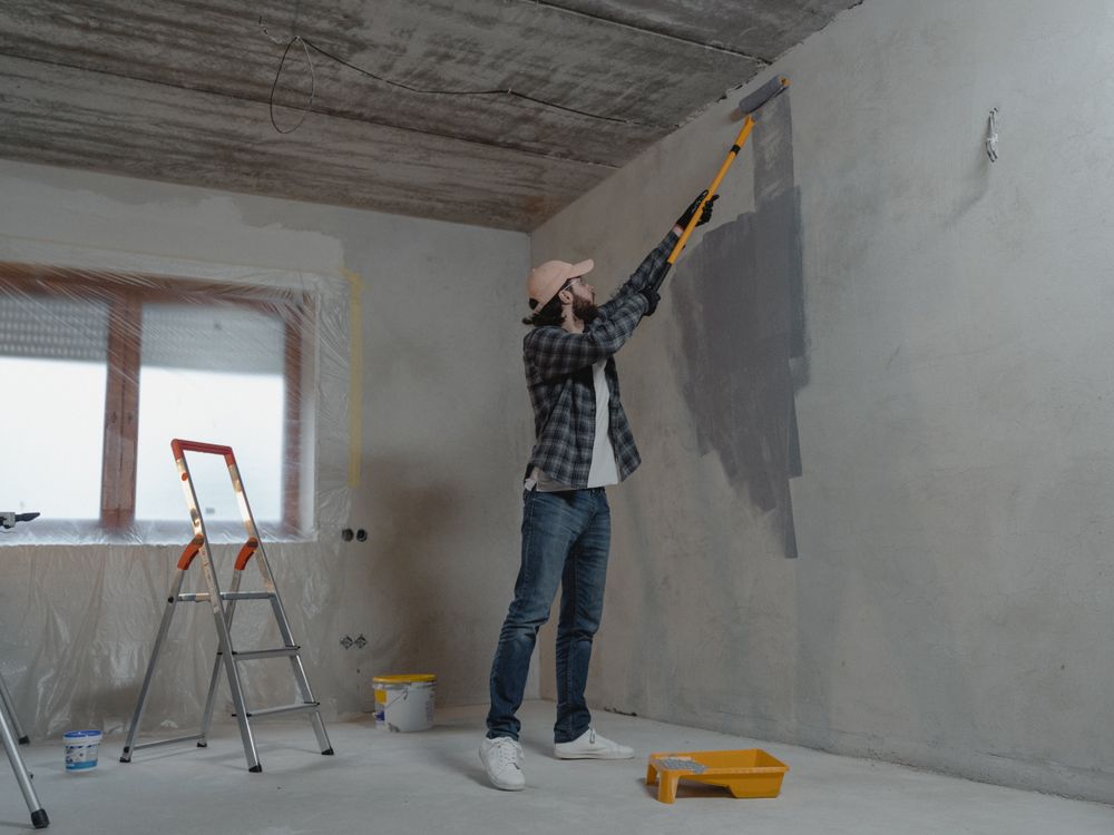 Painter working on wall with roller and ladder