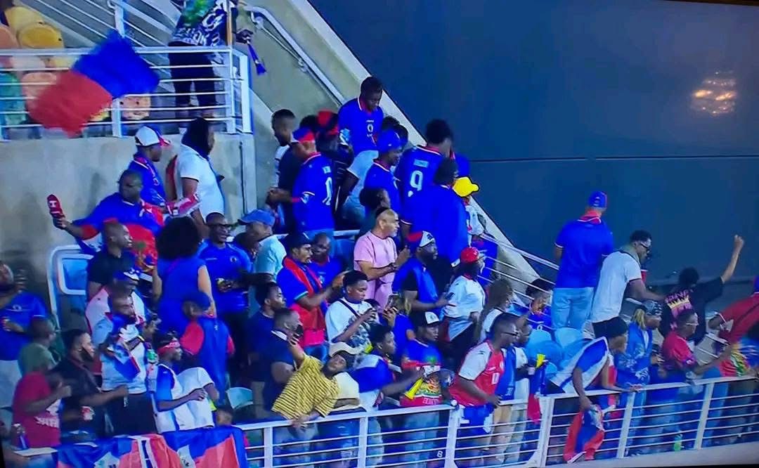 Supporters haïtiens en bleu et rouge, drapeaux à la main, dans les tribunes