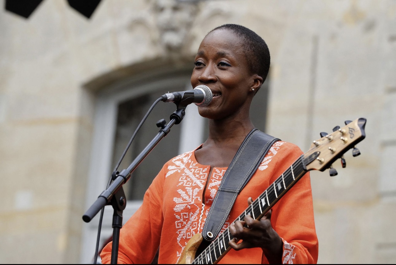 Rokia Traoré chantant, sa guitare en bandoulière