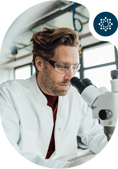 Scientist in lab coat looking through a microscope