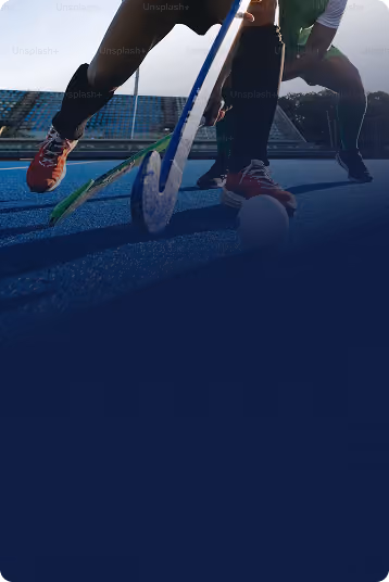 Two field hockey players with sticks in action on blue field during a game.