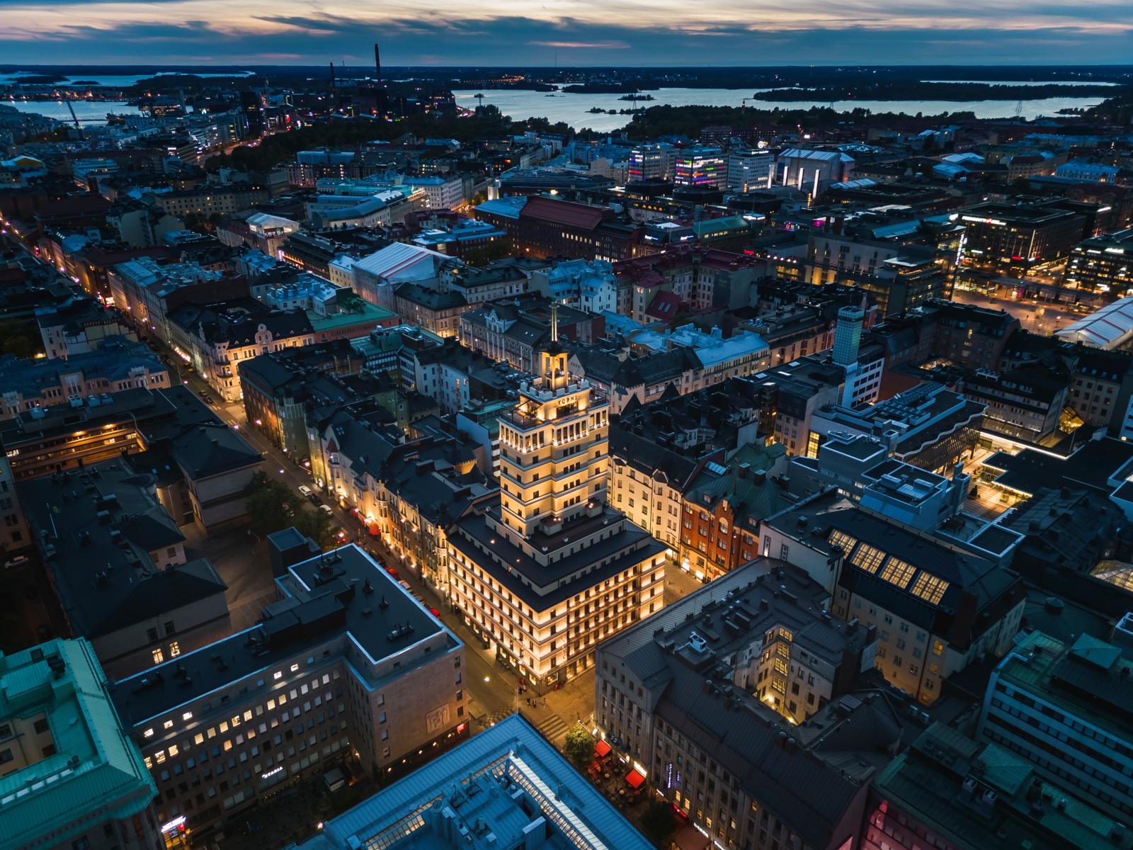 Hotelli Torni valaistuna Helsingin keskustassa ilmasta kuvattuna sinisen hetken aikaan
