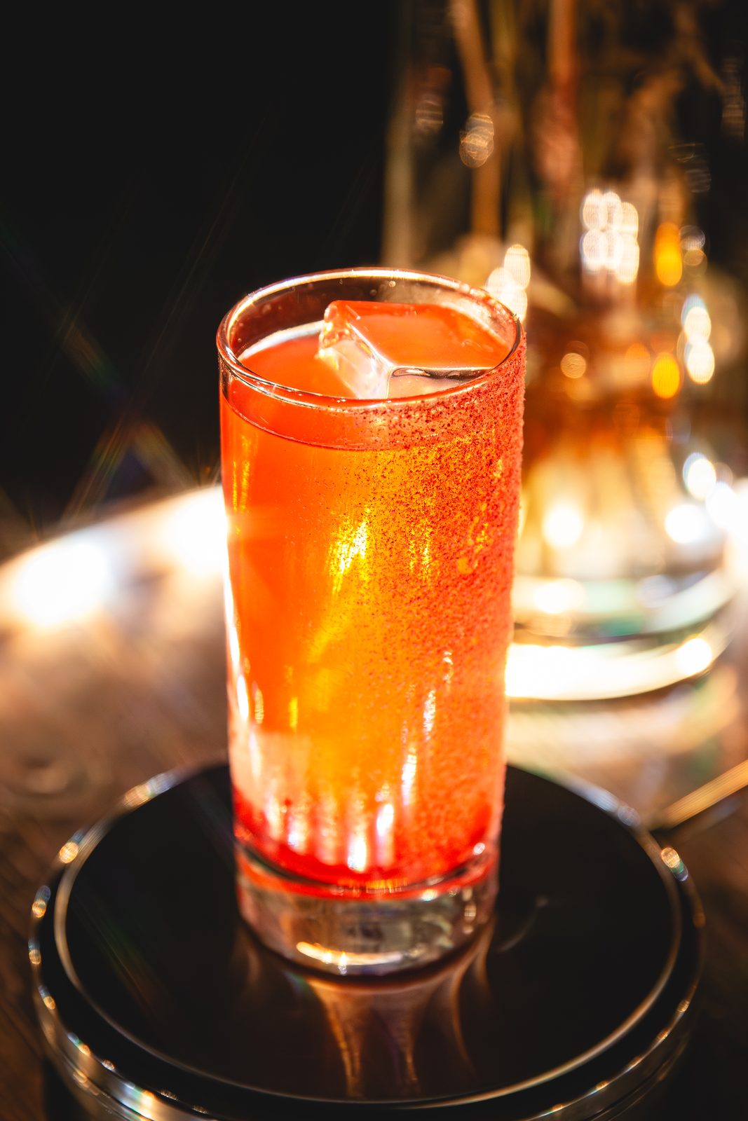A red highball cocktail on a lit serving stand at HDF Whiskey Edition