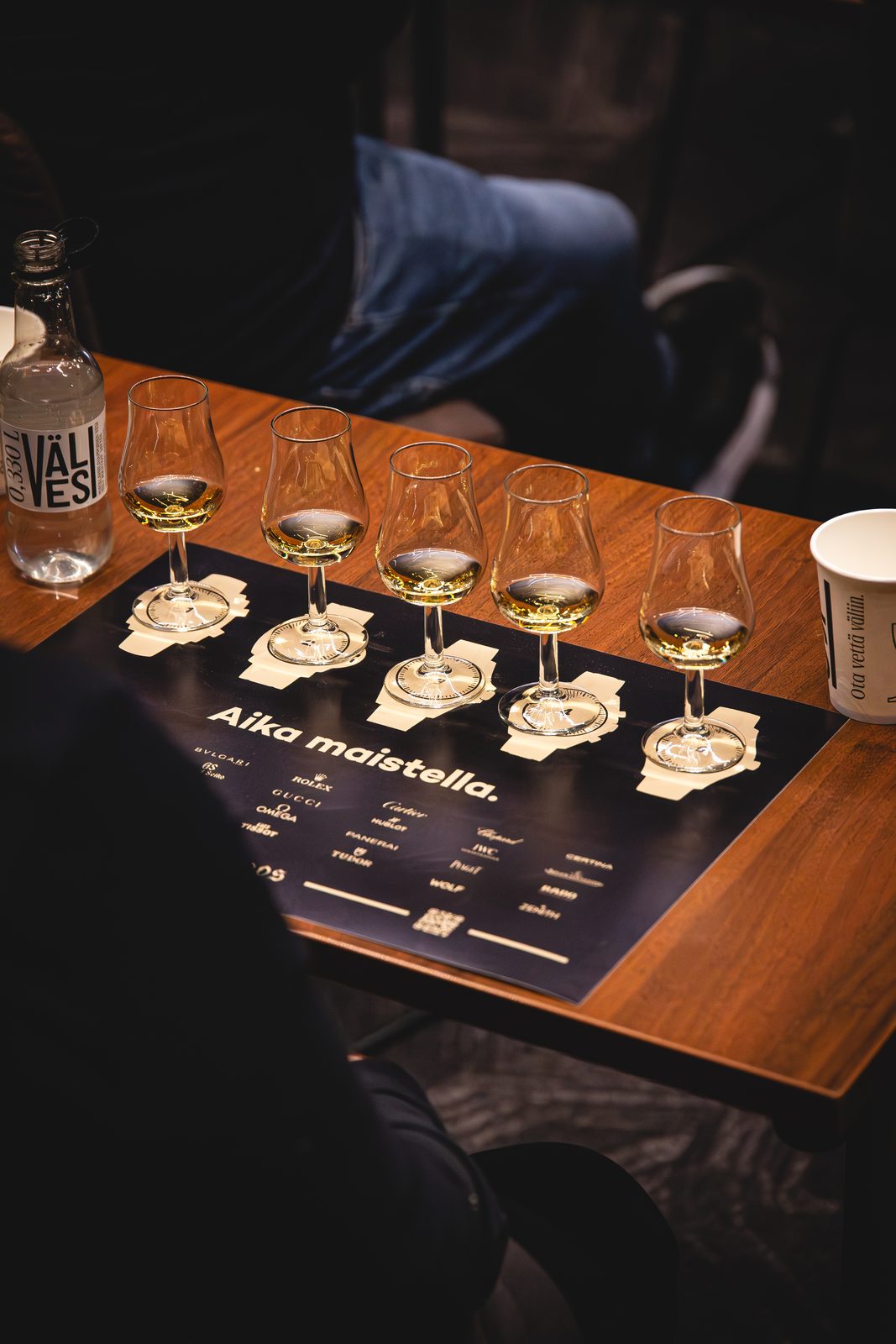 Five whisky tasting pours lined up on a tasting mat