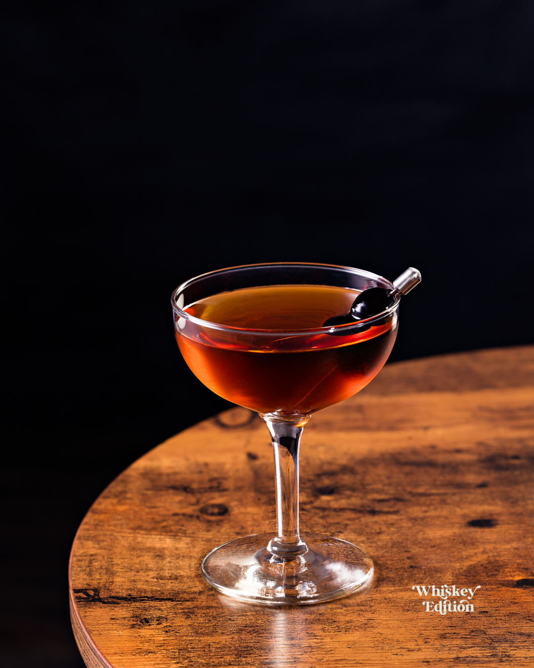 Manhattan in a coupe glass, garnished with a cocktail cherry