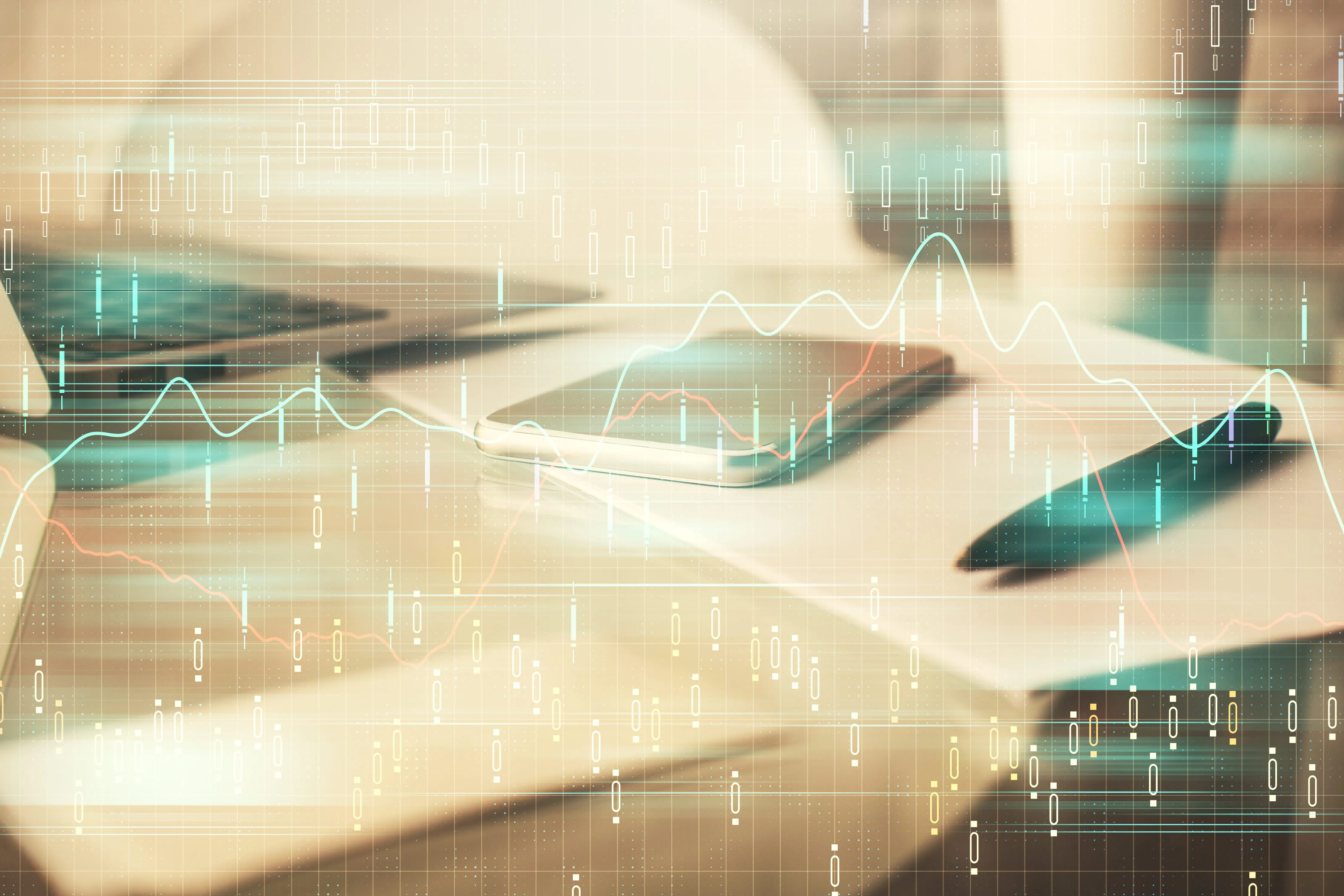 Double exposure of a smartphone, pen, and laptop on a desk with digital financial graphs overlayed.