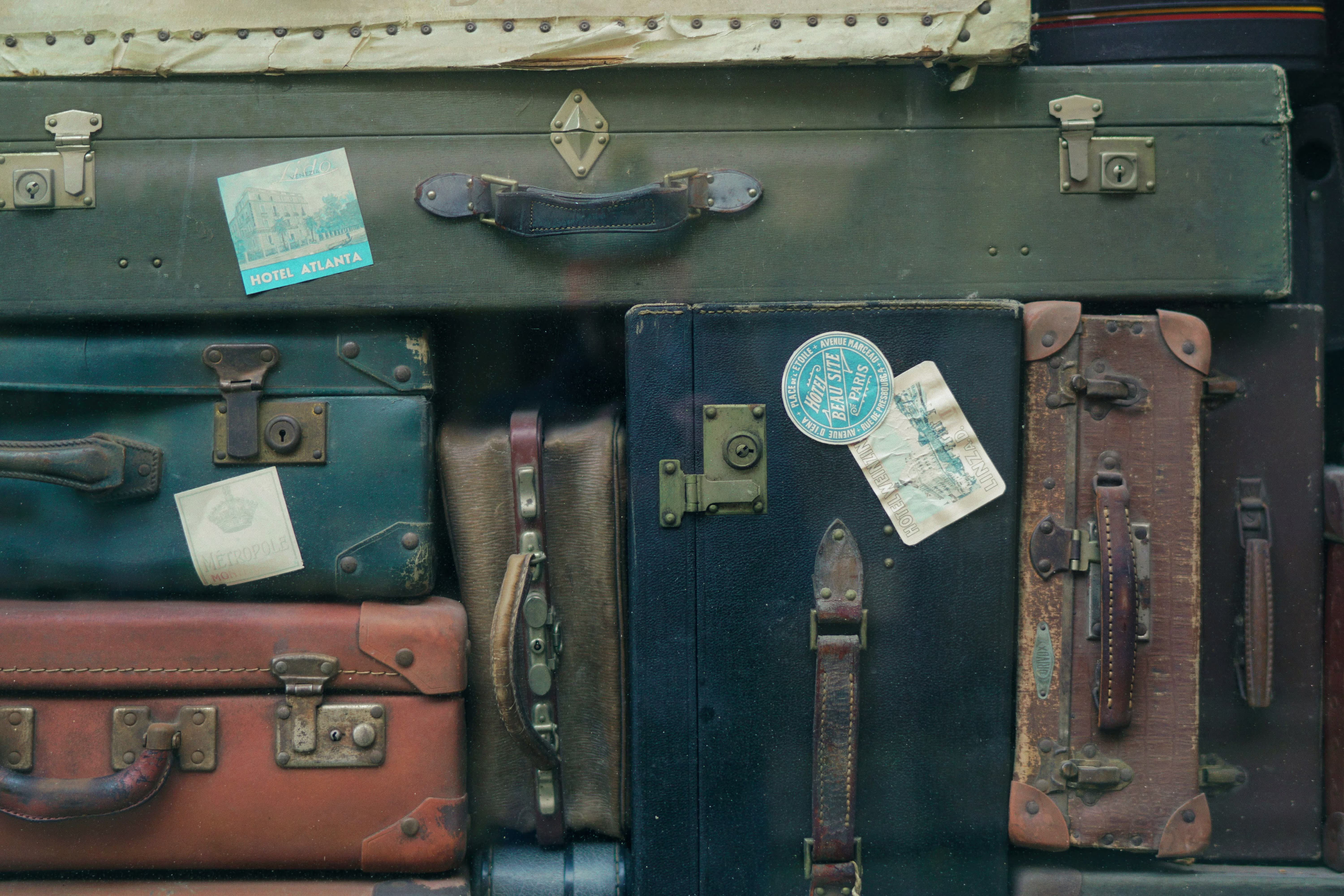 Stack of vintage suitcases with travel stickers from hotels including Hotel Atlanta and Paris.