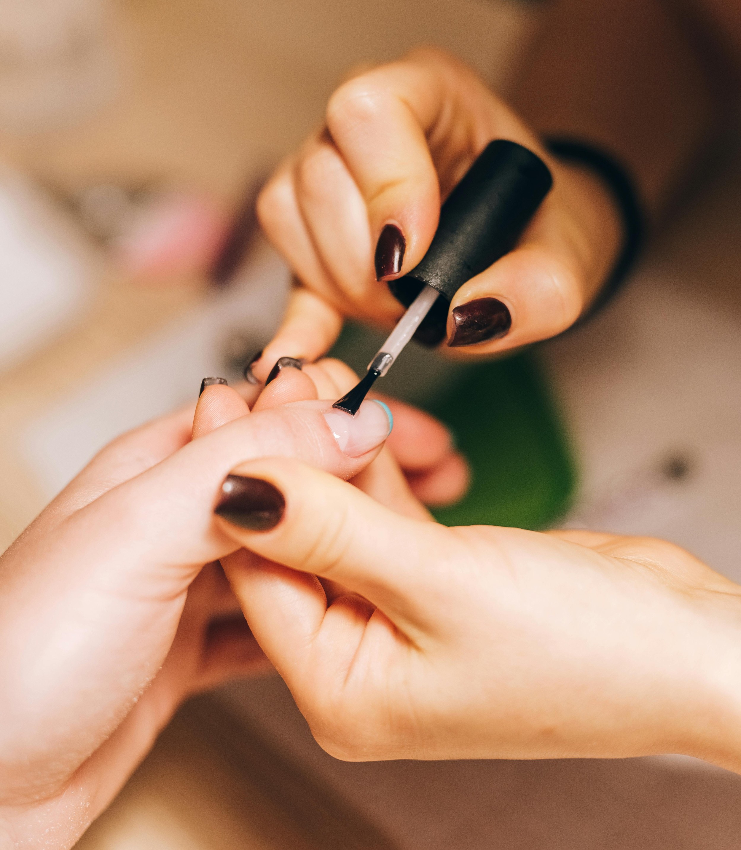 A nail technician applying dark polish to a guest's nails