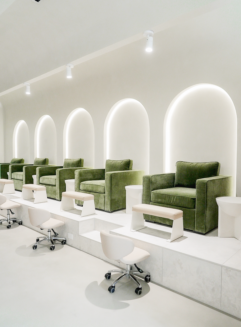 The pedicure lounge with green velvet chairs in lit archways