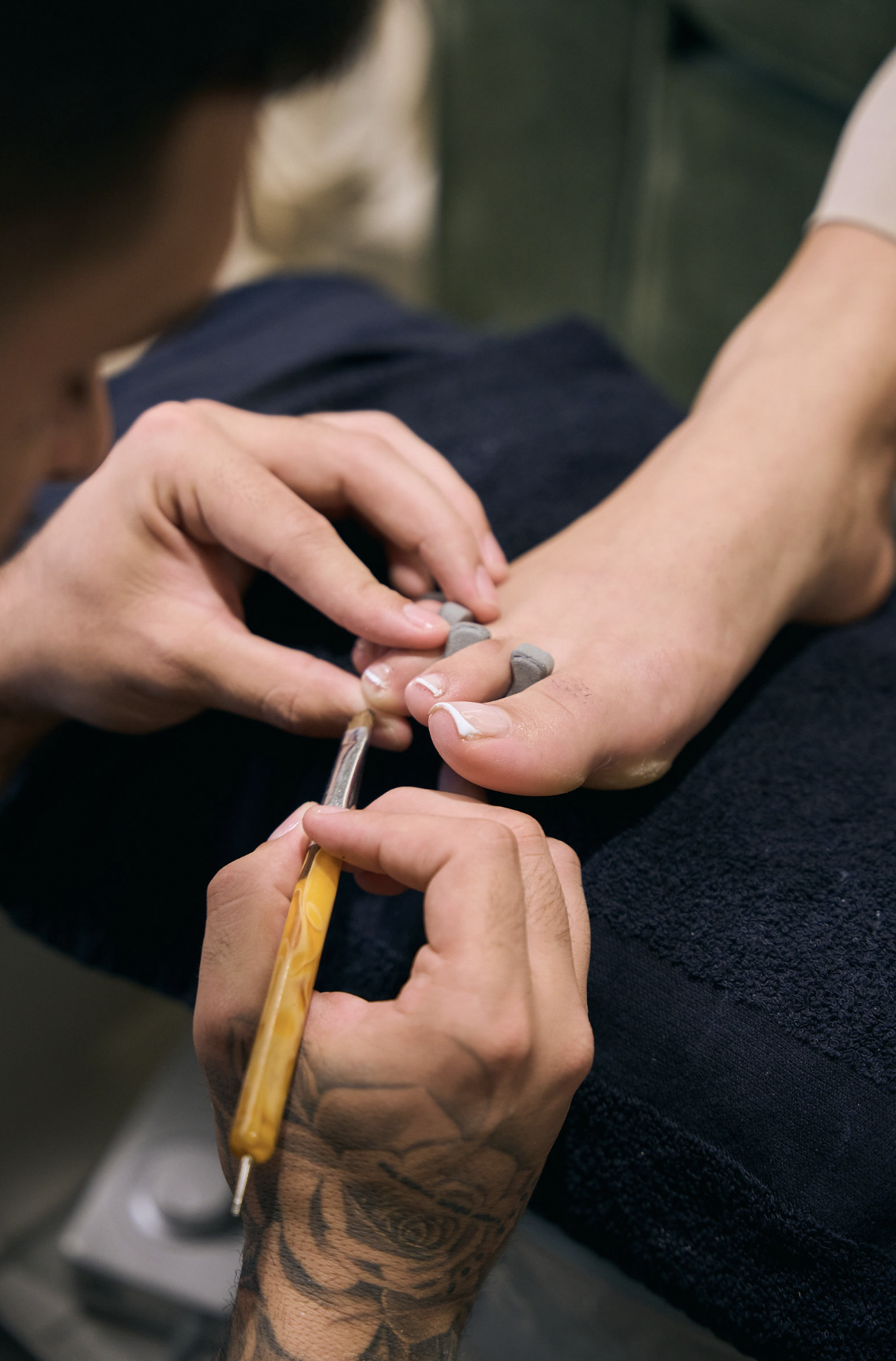 A nail technician carefully shaping a guest's nails