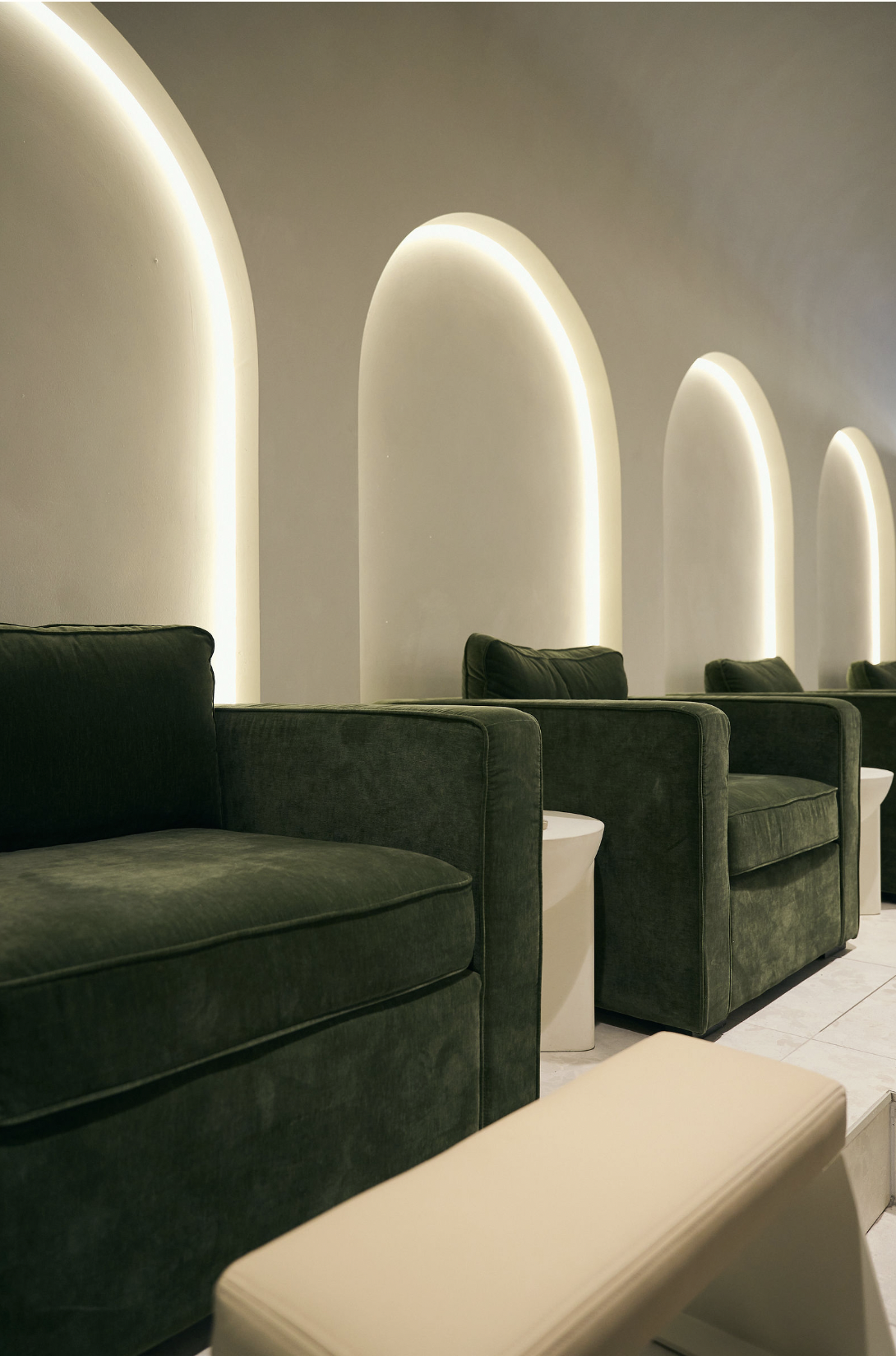 Pedicure chairs beneath the studio's backlit arches