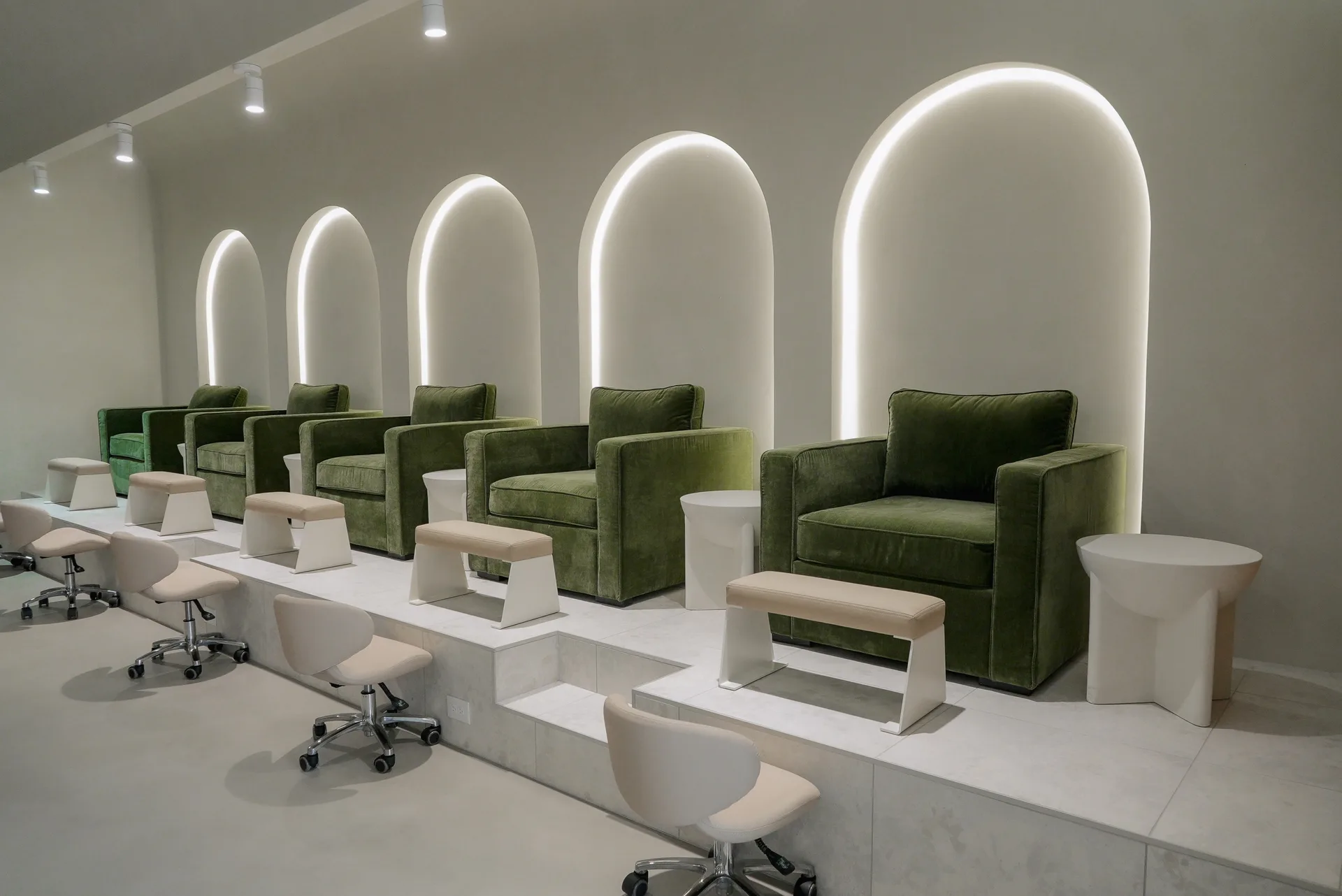 Pedicure lounge at Earth Nail Spa — green velvet chairs in lit archways
