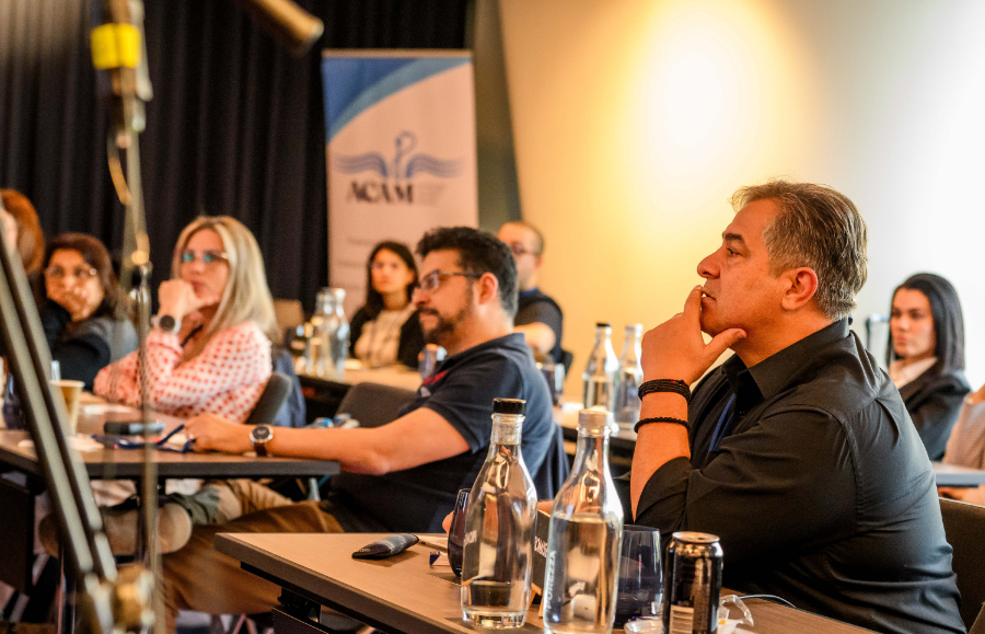 Audience listening to a presentation at an ACAM event