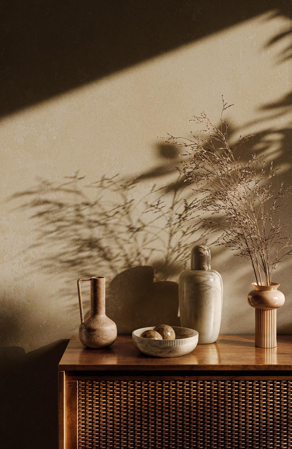 Wooden sideboard with ceramic vase, bowl with decorative balls, stone bottle, and dried plants casting shadows.