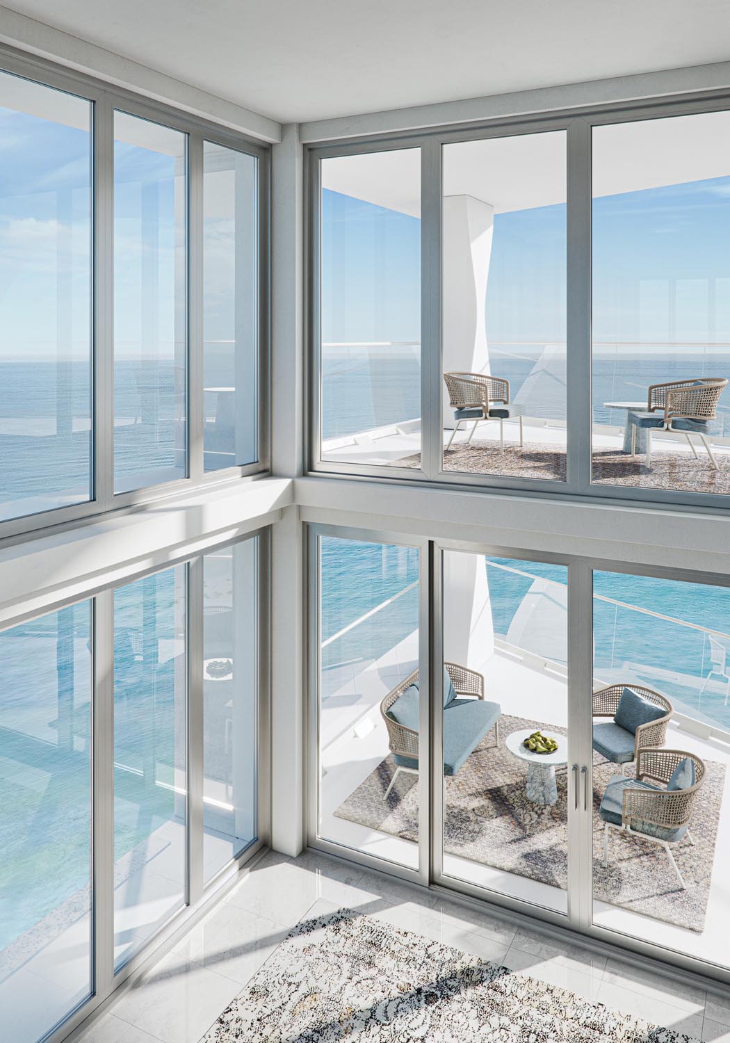 Modern balcony with wicker chairs, sofa, and table overlooking calm blue ocean under clear sky.