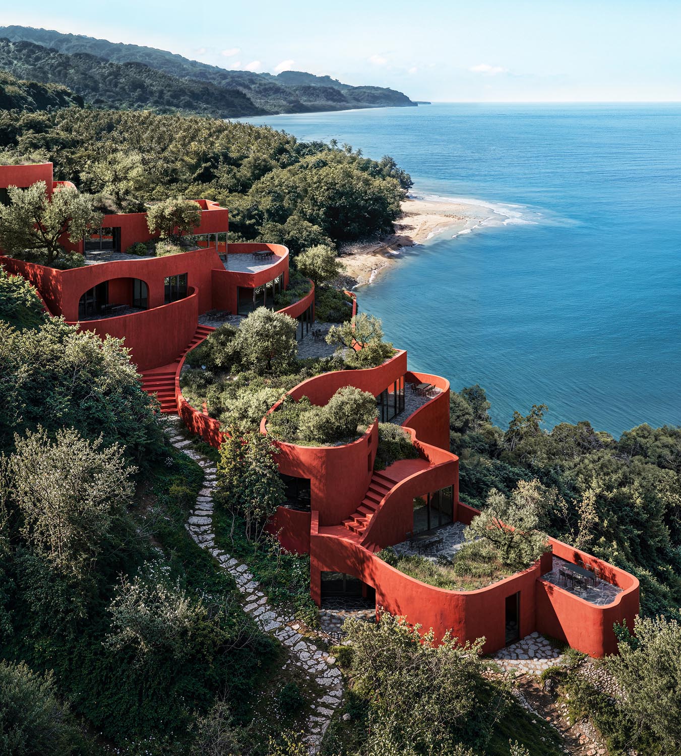 Aerial view of terracotta villas nestled in lush coastal vegetation beside the blue sea.